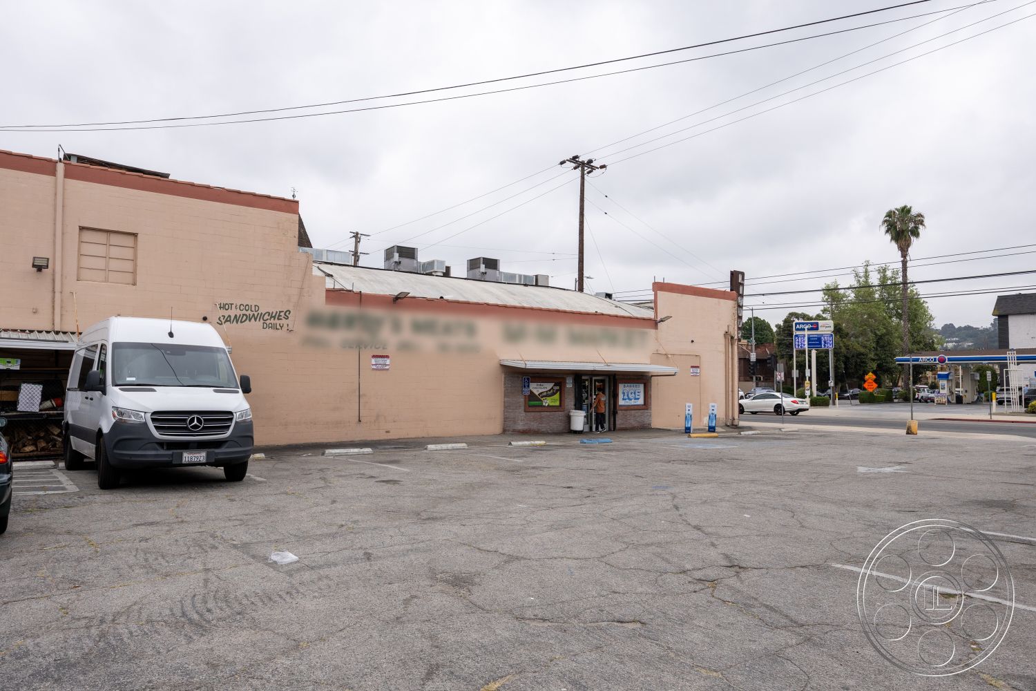 Shop 128 - exterior, paved driveway, flat roof, urban setting, utility poles, concrete parking lot, palm trees in landscape, large storefront windows, single-story commercial building, stucco building exterior, metal awning, signage on building facade
