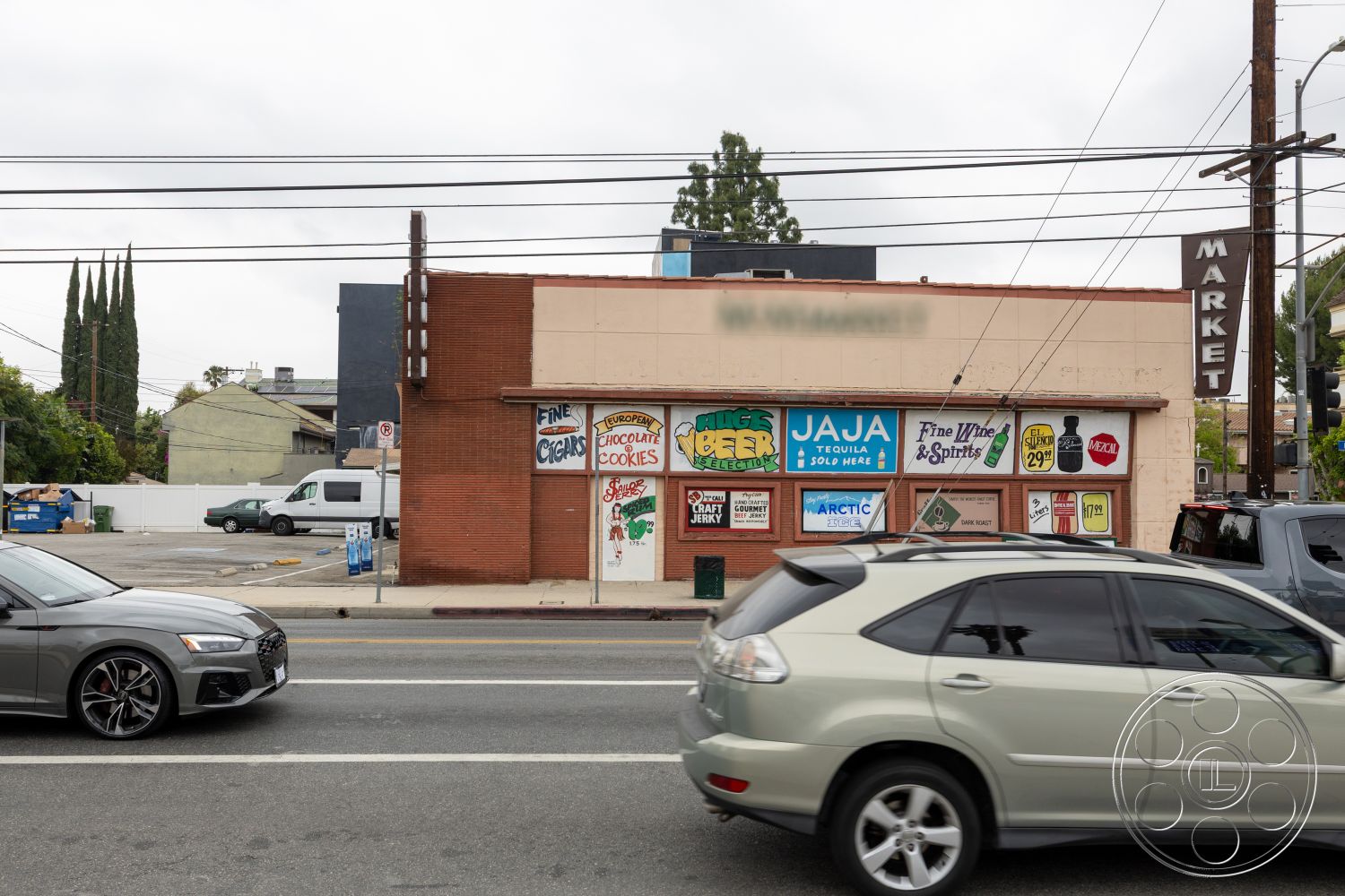 Shop 128 - exterior, asphalt parking lot, paved street, flat roof structure, surrounding urban environment, landscaped area with trees, brick storefront facade, painted sign details, large glass display windows