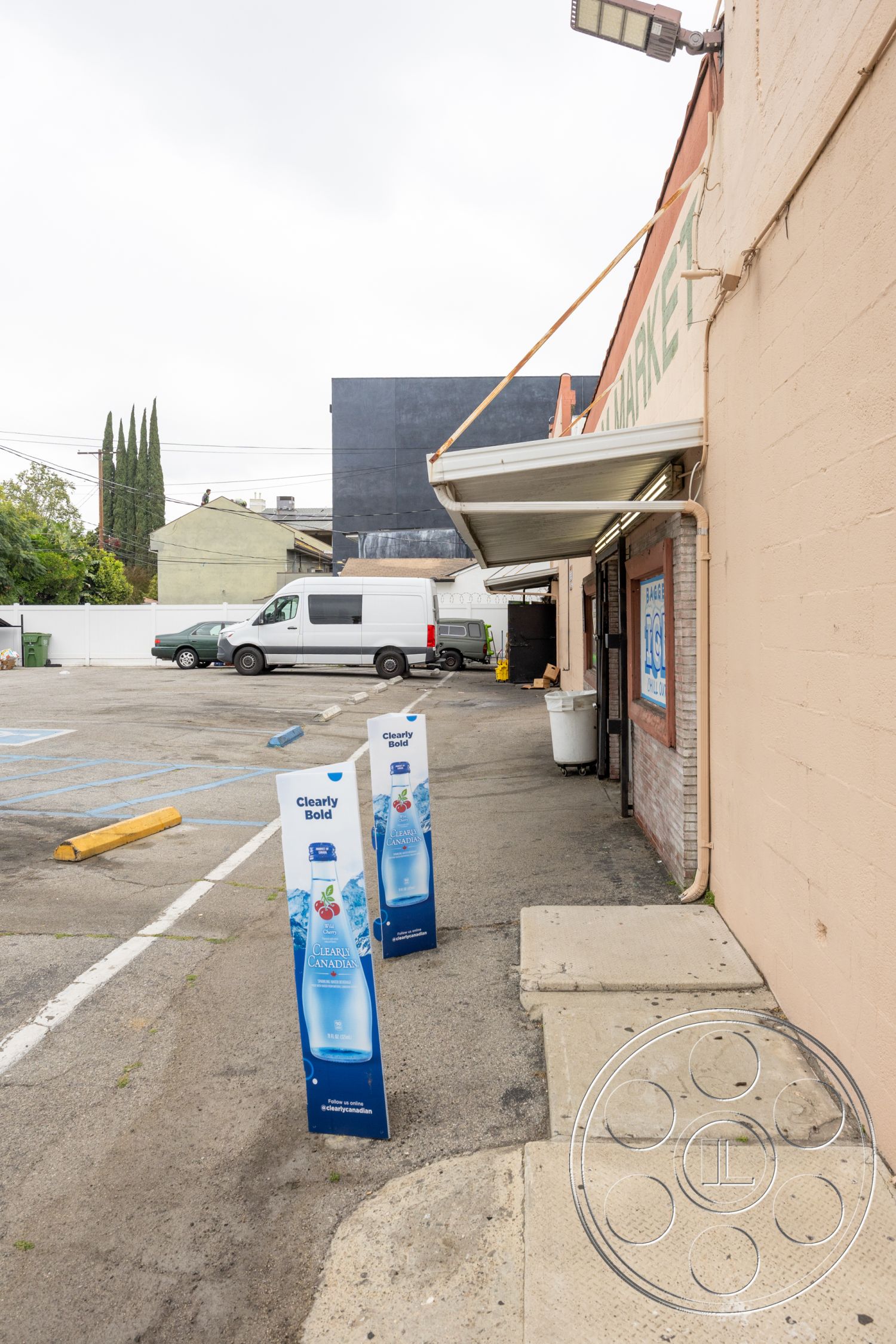 Shop 128 - exterior, concrete sidewalk, asphalt parking surface, vehicle parking area, metal awning, brick building walls, stepped concrete pad, plastic signage, parking lot with painted lines, outdoor market setting