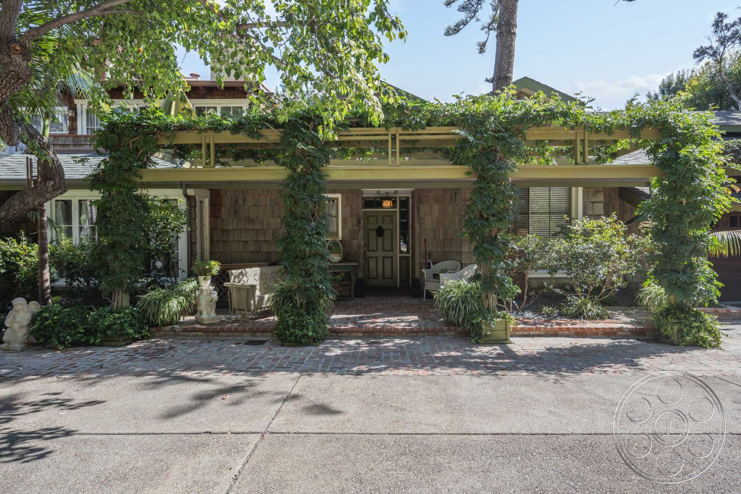 Americana 48 - exterior, landscaped garden, potted plants, shingle siding, covered porch, brick pathway, vibrant greenery, wooden front door, green pergola, front seating area, decorative garden statues, traditional Craftsman style