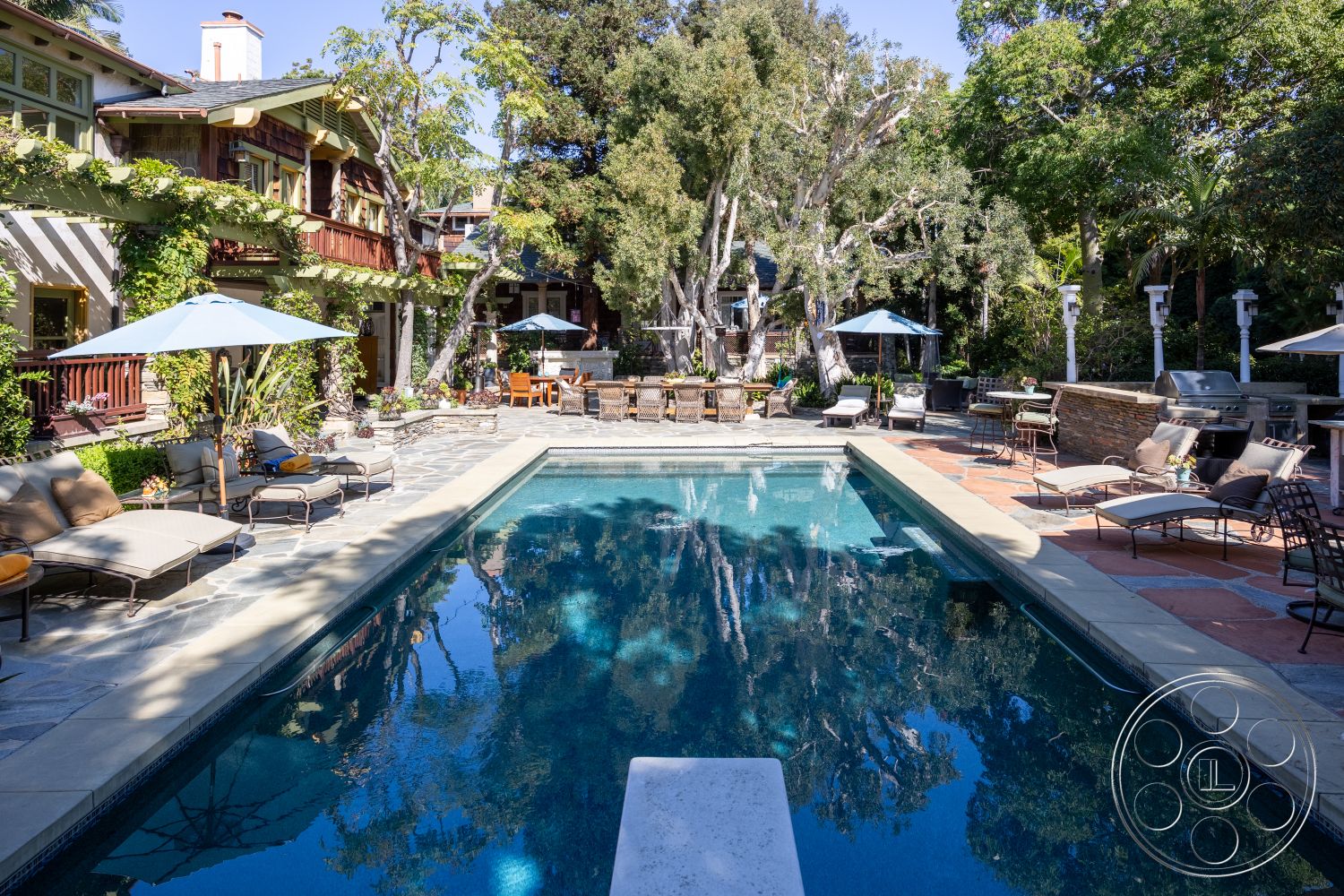 Americana 48 - lush greenery, modern outdoor furniture, wooden beams, exposed brick wall, outdoor dining area, stainless steel grill, residential backyard, wood railings, outdoor umbrellas, stone pool deck, landscaped garden setting, rectangle pool, textured stone patio flooring, flagstone walkways, wood deck chairs