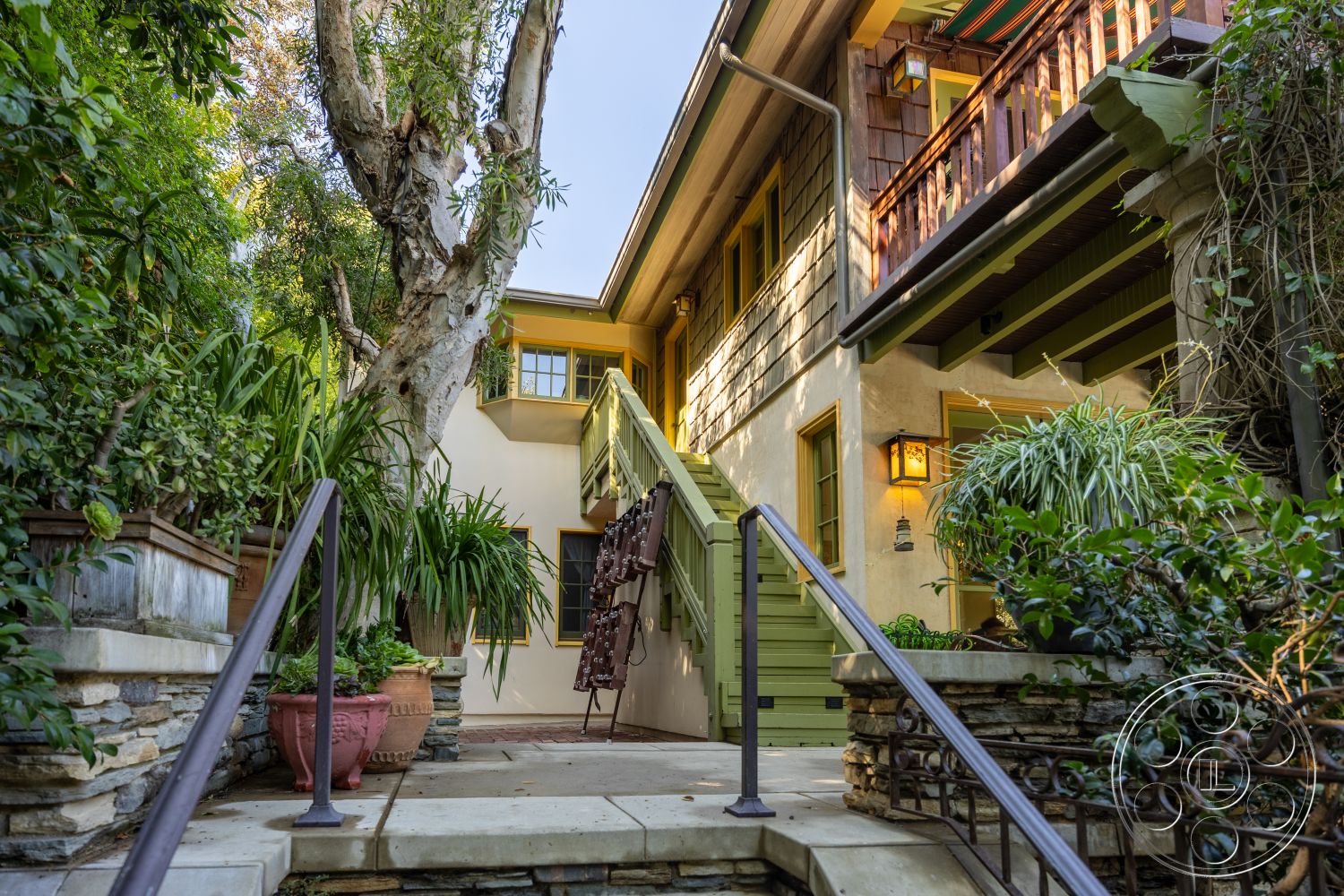 Americana 48 - planter boxes, slate stone pathway, traditional architectural style, wooden handrail, landscaped garden area, stone patio stairs, exposed wood shingle siding, green wooden balcony, yellow window frames, three-story home, interior staircase with wooden steps