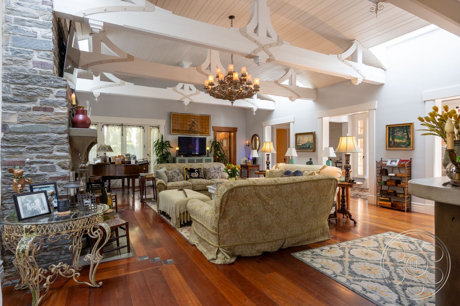 Americana 48 - decorative area rug, open layout, glass coffee table, artwork on walls, large windows for natural light, entertaining space, chandelier lighting, arched doorways, exposed wood ceiling beams, hardwood living room floors, stone fireplace wall, wooden furniture accents, plush upholstered sofa, painted wall panels