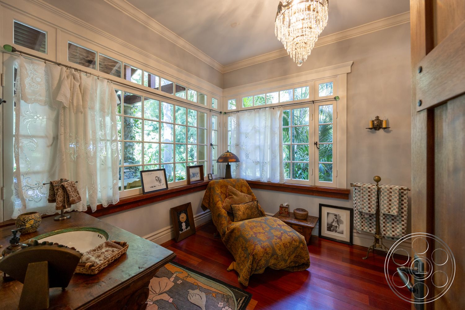 Americana 48 - natural light, hardwood flooring, decorative artwork, textured wall finish, chandelier lighting, vintage armchair, wall-mounted sconces, wood window trim, lace curtains, wooden window seats, built-in sink, plants visible outside windows