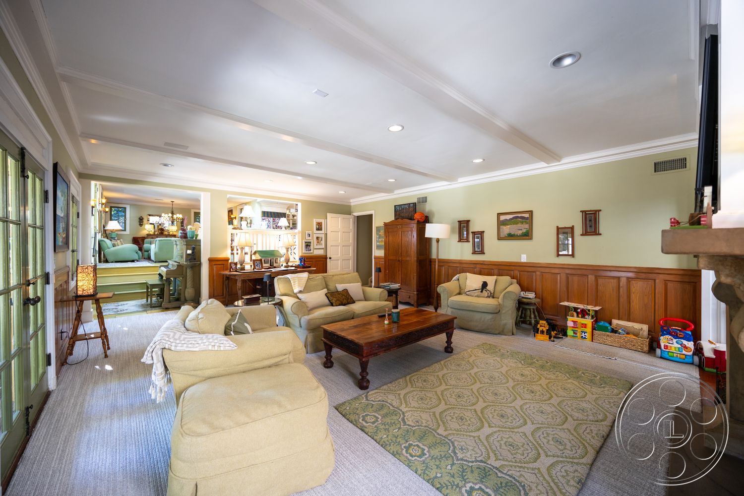 Americana 48 - neutral color palette, artwork on walls, built-in shelving, floor-to-ceiling windows, hardwood floor, textured plaster walls, area rug with intricate patterns, formal dining area, rectangular coffee table, coffered ceiling details, wood paneling walls, traditional style decor, plush upholstered sofas, lighting fixtures with lampshades