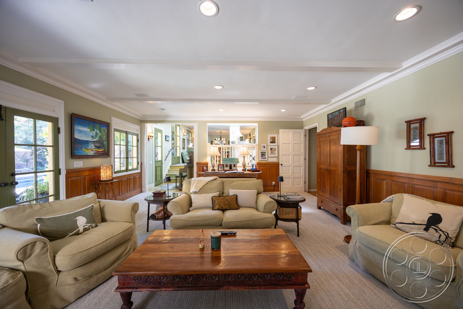 Americana 48 - wood coffee table, cozy seating arrangement, decorative wall art, textured plaster walls, floor lamps, glass door access, multiple windows, light gray sofa, interior living room, built-in shelving unit, crown molding details, green accent walls, hardwood wainscoting, carpet living room flooring, traditional armoire