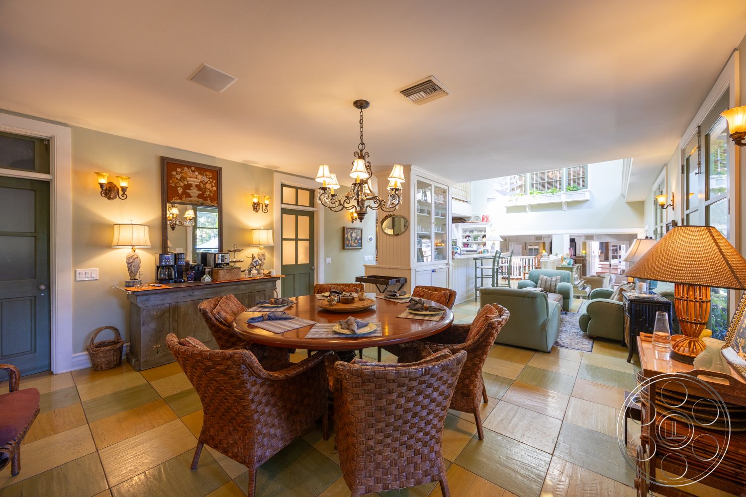 Americana 48 - neutral color palette, open floor plan, wooden cabinetry, kitchenette area, stylish table lamp, glass patio doors, wall-mounted sconces, round wooden dining table, exposed wood ceiling beams, white painted walls, crown molding details, decorative wall mirror, wicker dining chairs, mixed colored tile flooring, light pendant chandelier