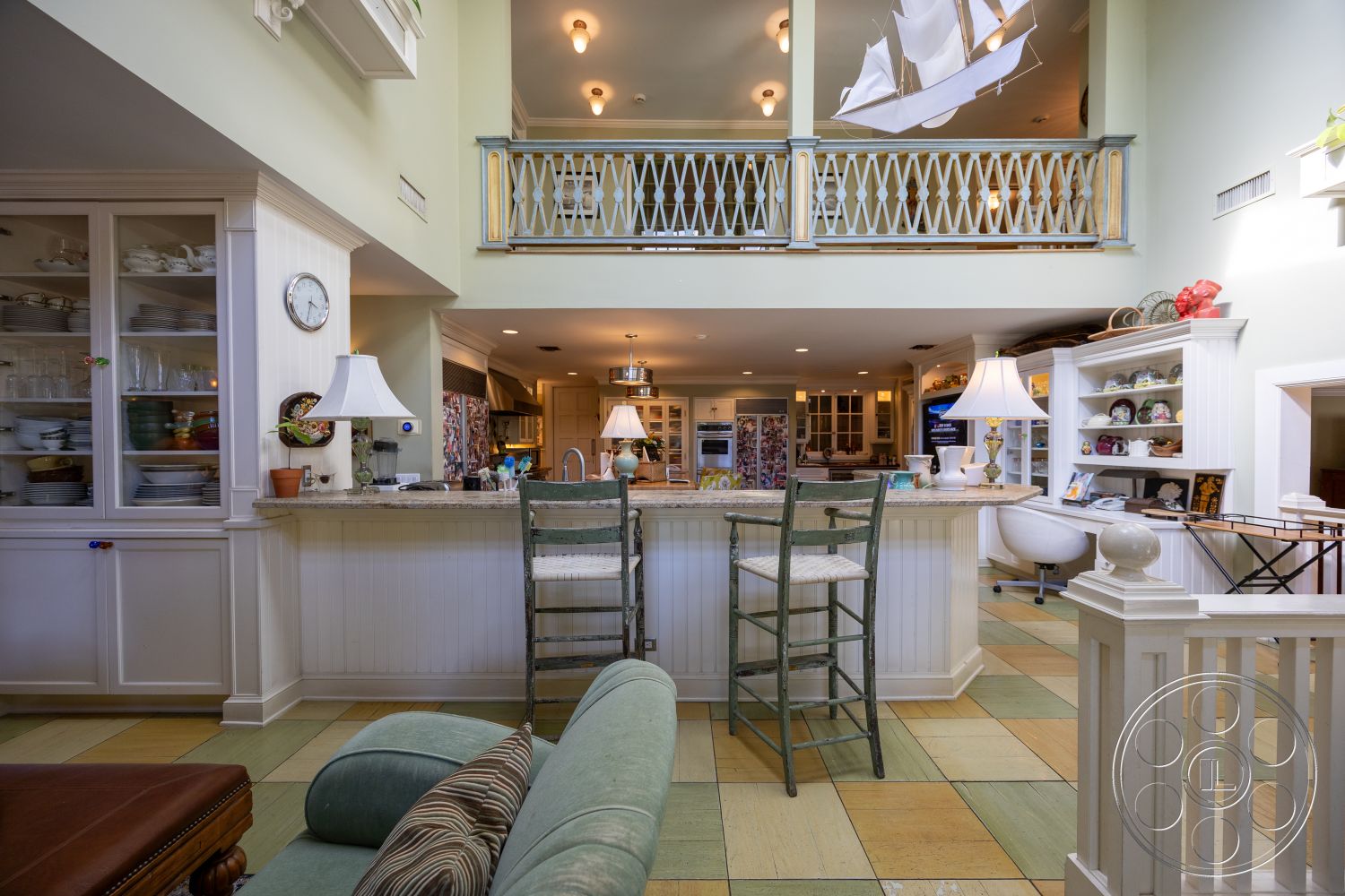 Americana 48 - tile flooring, wooden bar stools, dining area, open concept layout, living room area, kitchen area, light fixtures, marble countertop, textured plaster walls, glass display cabinet, built-in cabinetry, green painted walls, beadboard kitchen island, vintage pendant lighting, white painted wood paneling, shiplap accents, open railing balcony, decorative dish display