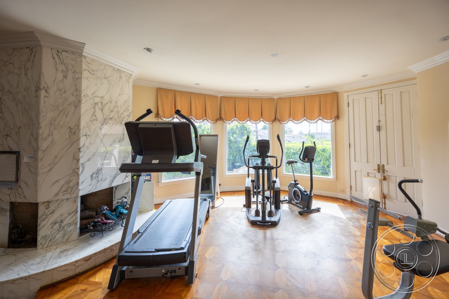 Mansion 146 - exercise equipment, double doors, natural light from windows, wood parquet flooring, decorative window valance, marble fireplace surround, white ceiling with recessed lighting, bay window design, corner fireplace