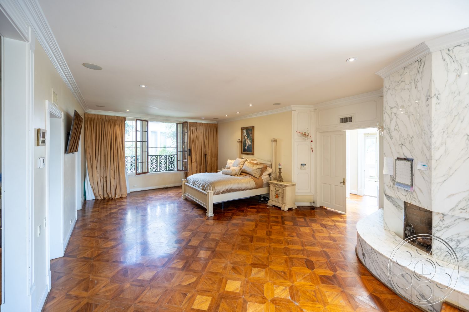 Mansion 146 - floor-to-ceiling windows, luxurious bedding, marble fireplace surround, coffered ceiling details, decorative wrought iron balcony railing, elegant curtain drapery, soft beige wall treatment, hardwood parquet bedroom flooring