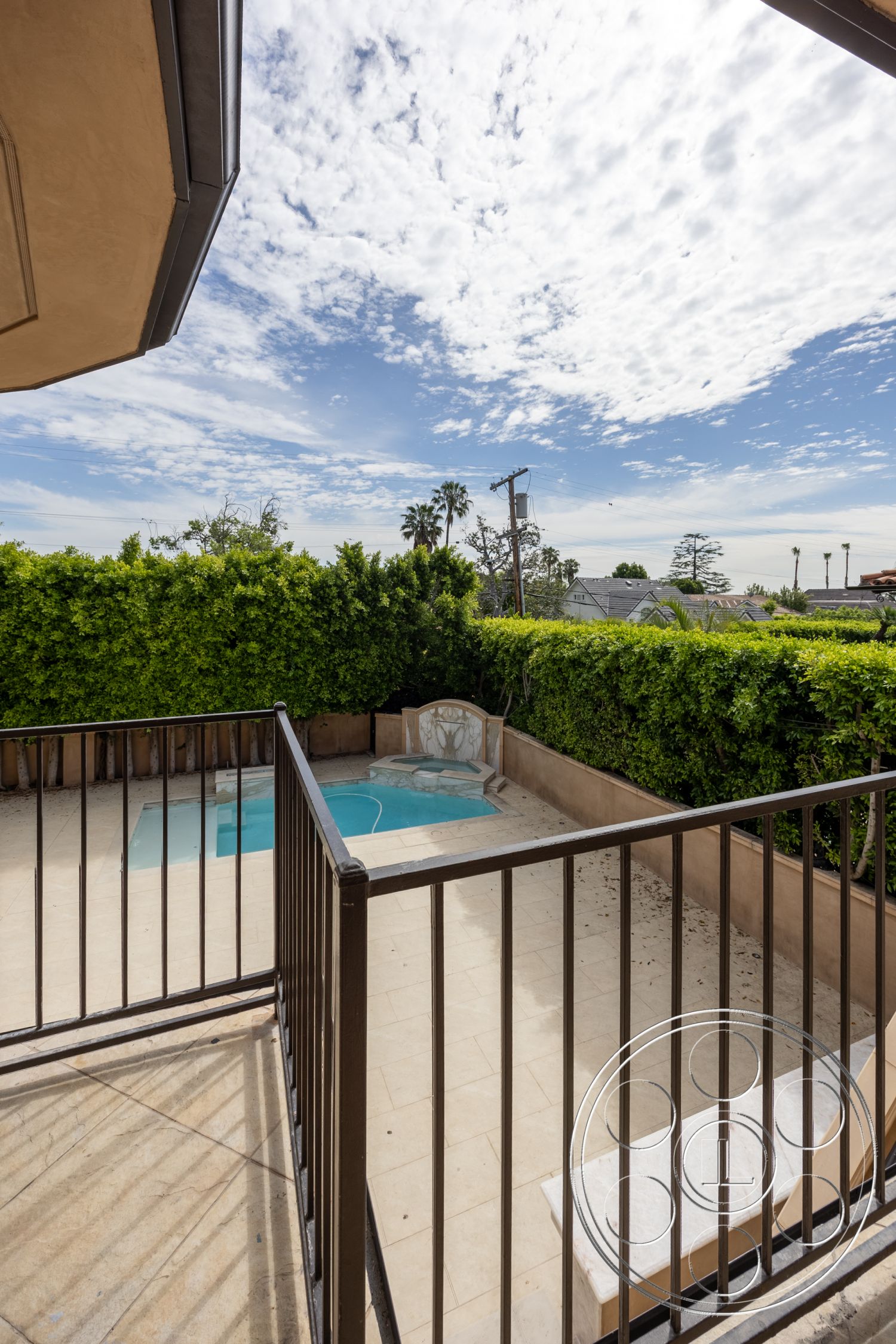Mansion 146 - exterior, urban setting, black metal railing, clear blue sky, lush green hedges, concrete pool deck, rectangle pool, brown decorative wall, tan ceramic tile flooring, partial ocean view