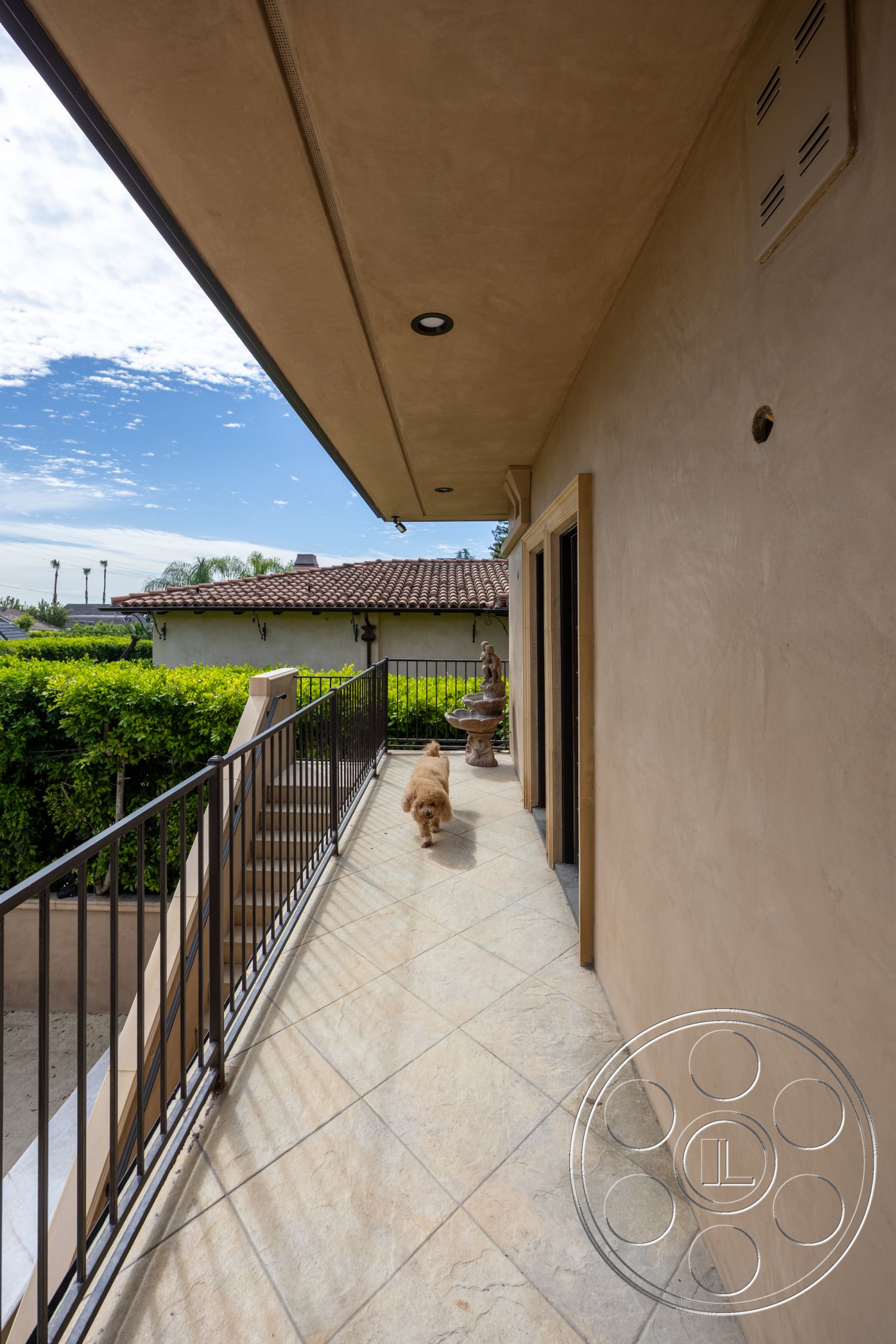 Mansion 146 - exterior, surrounding greenery, paved pathway, stucco walls, overhanging roof eaves, metal stair railings, outdoor stairway, built-in lighting fixtures, tile walkway flooring, decorative water fountain