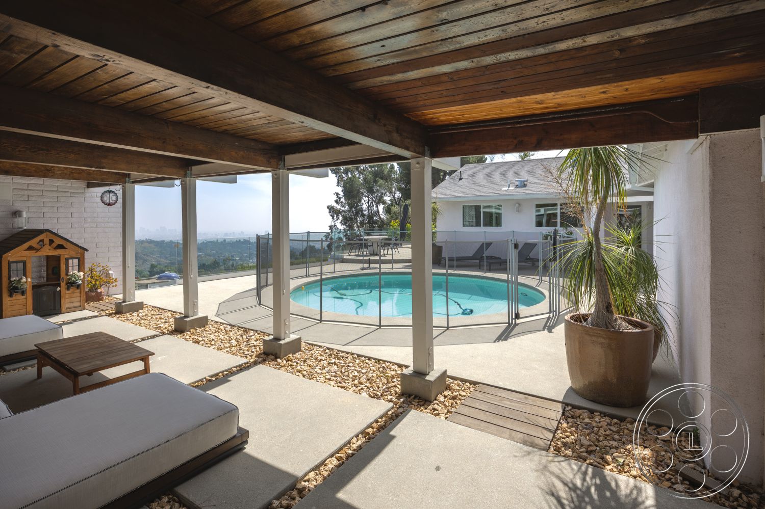 Retro 288 - exterior, outdoor living space, glass pool fence, rectangular pool, wooden outdoor furniture, mountain view setting, wood beam ceiling, white painted walls, concrete patio floor, landscaped garden with rocks, modern home style