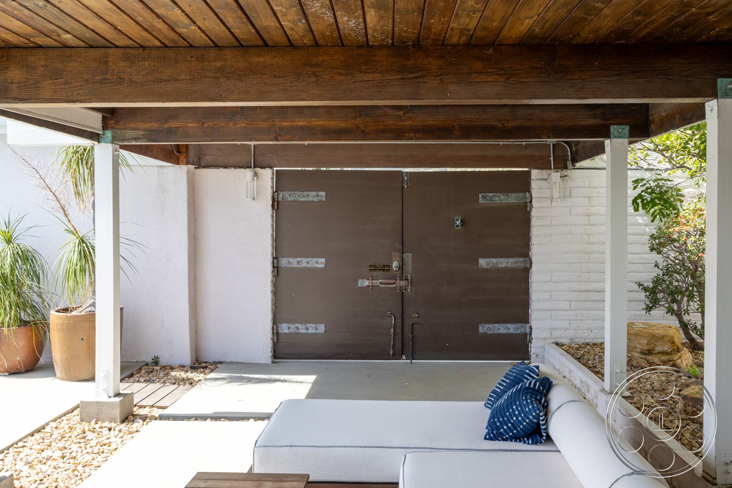 Retro 288 - exterior, minimalist design elements, outdoor seating area, wood ceiling beams, landscaped garden area, natural stone border, concrete patio floor, smooth white stucco walls, large metal entrance doors, decorative outdoor planter, geometric outdoor cushions