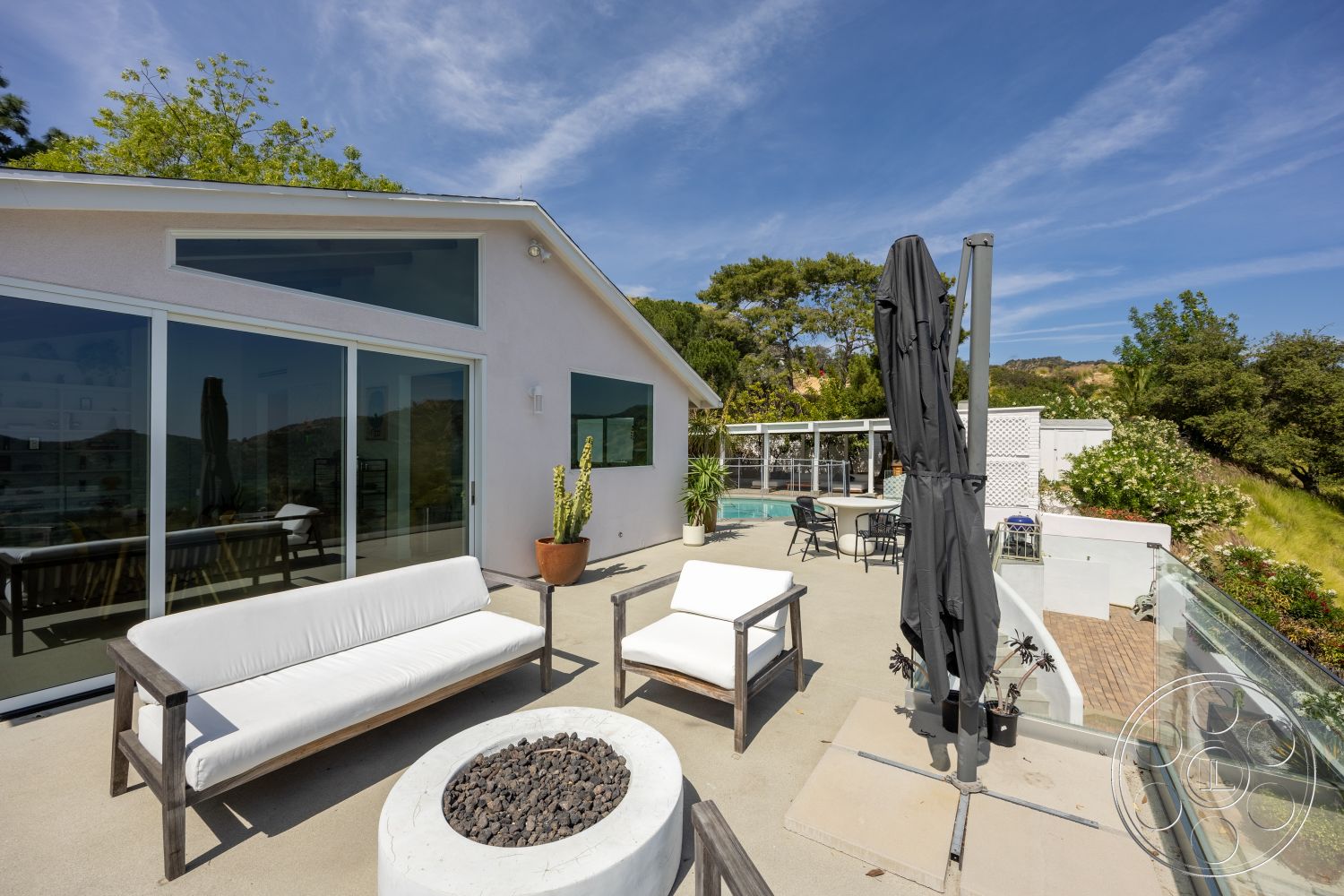 Retro 288 - exterior, glass sliding doors, large windows for natural light, rectangular swimming pool, mountain view setting, landscaped garden area, concrete patio flooring, clean architectural lines, wooden outdoor seating, modern white stucco walls, round fire pit with black stones, metal patio umbrella stand