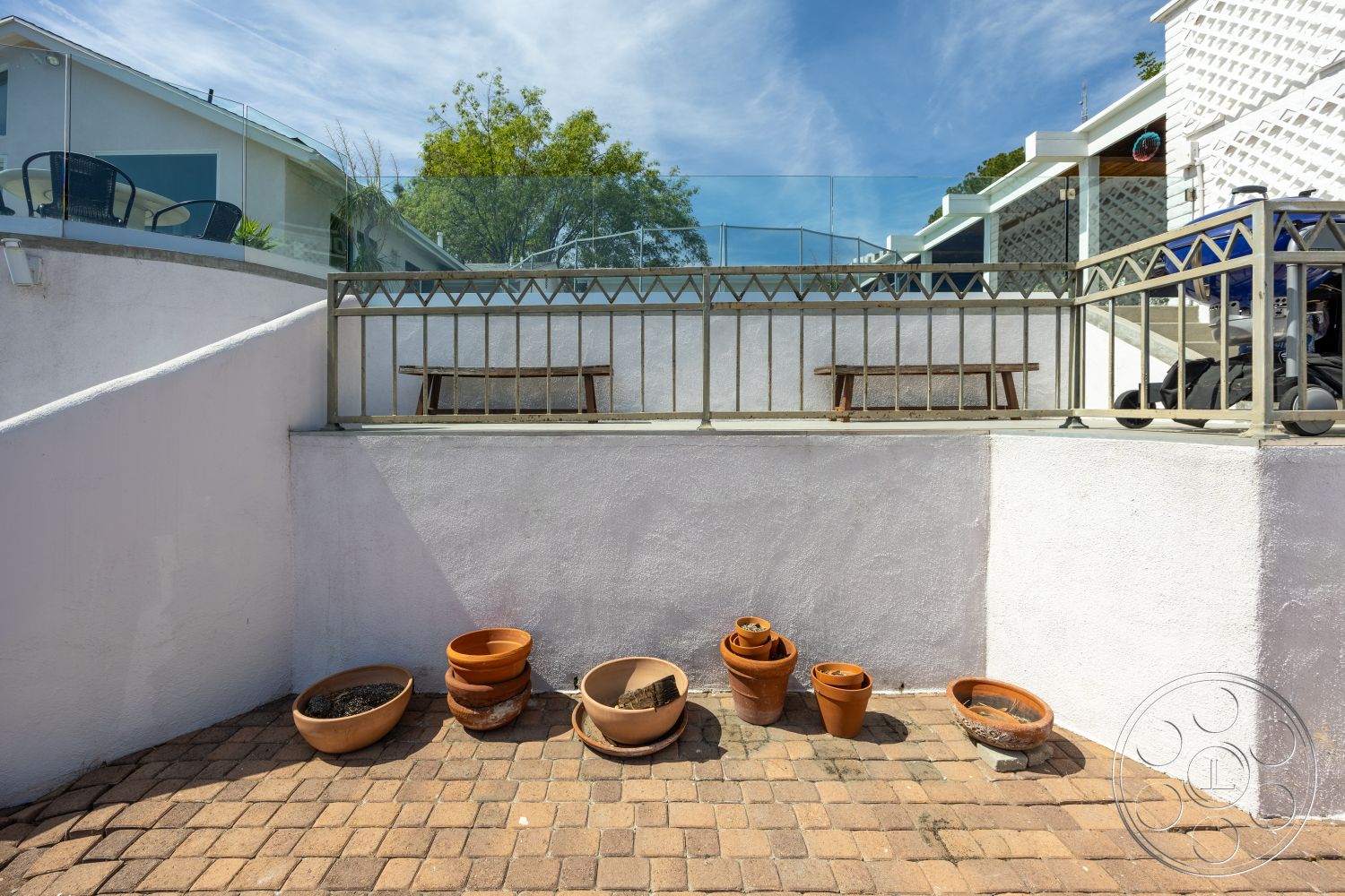 Retro 288 - exterior, white stucco walls, glass railing, concrete wall, outdoor living space, wooden bench seating, landscaped garden setting, brick patio flooring, terracotta plant pots
