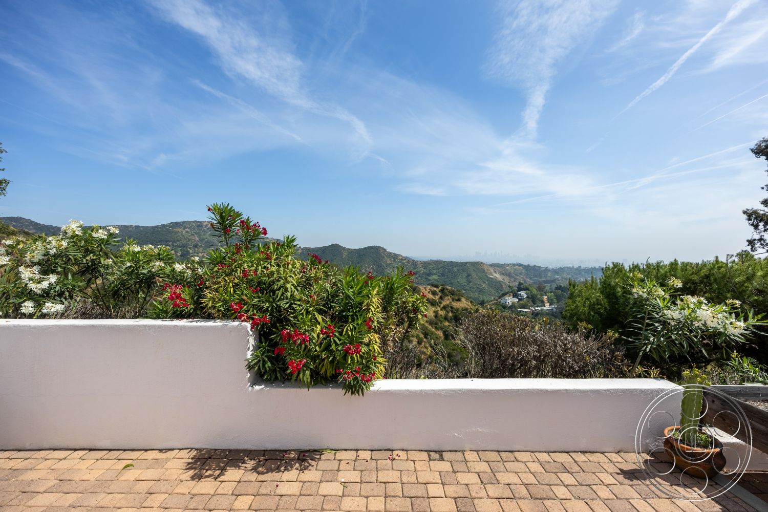 Retro 288 - exterior, outdoor living space, flowering shrubs, mountain view, clear blue sky, white stucco wall, landscaped garden area, paver patio flooring, terraced hillside, desert climate garden