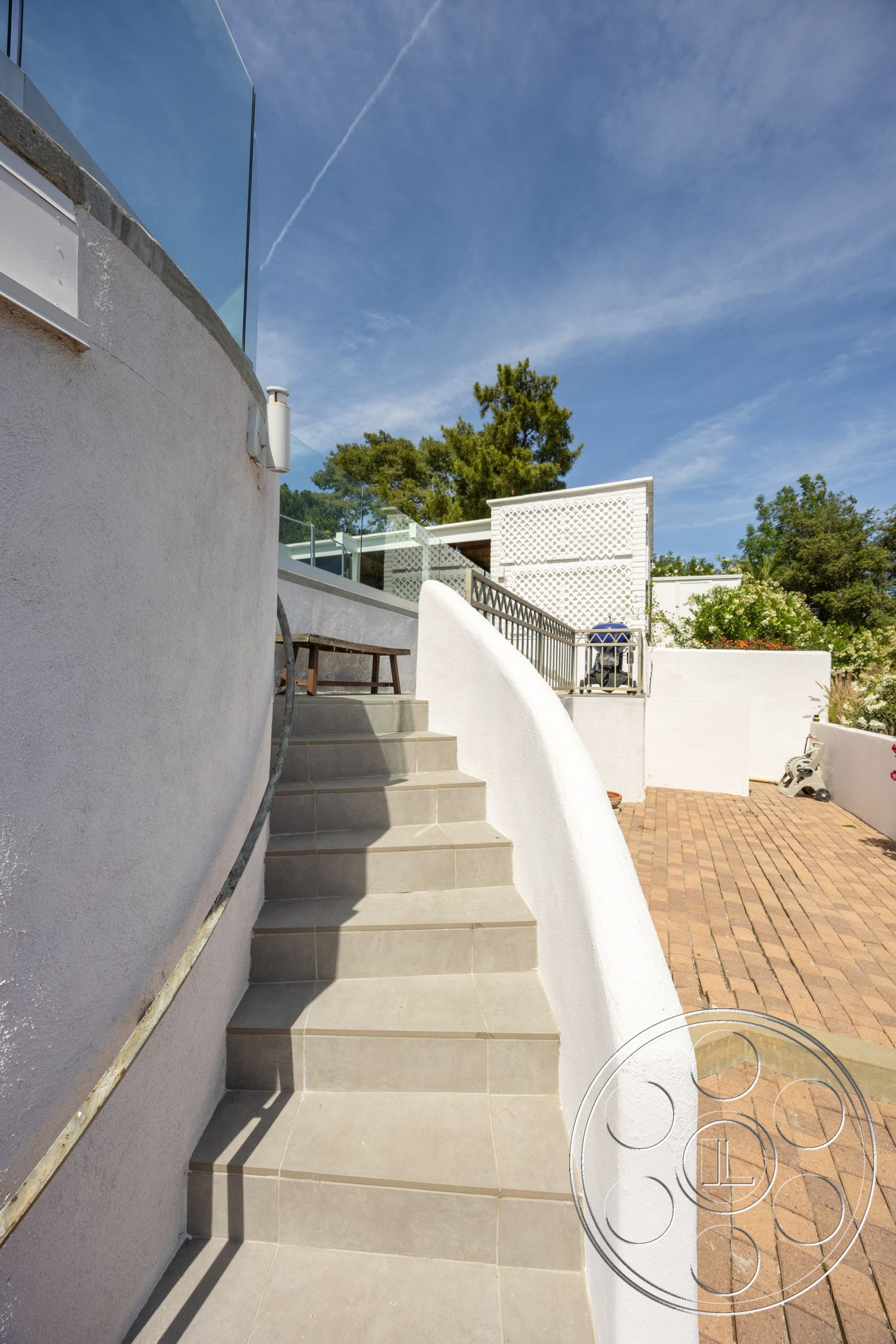 Retro 288 - exterior, white stucco walls, outdoor seating area, glass railing, modern architectural style, landscaped garden area, brick patio flooring, curved concrete steps, grey ceramic tile flooring