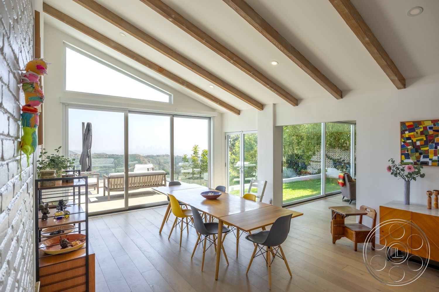Retro 288 - glass sliding doors, natural landscape view, exposed wood ceiling beams, white painted walls, floor-to-ceiling glass windows, outdoor patio access, contemporary dining table, hardwood dining room floors, colorful abstract wall art