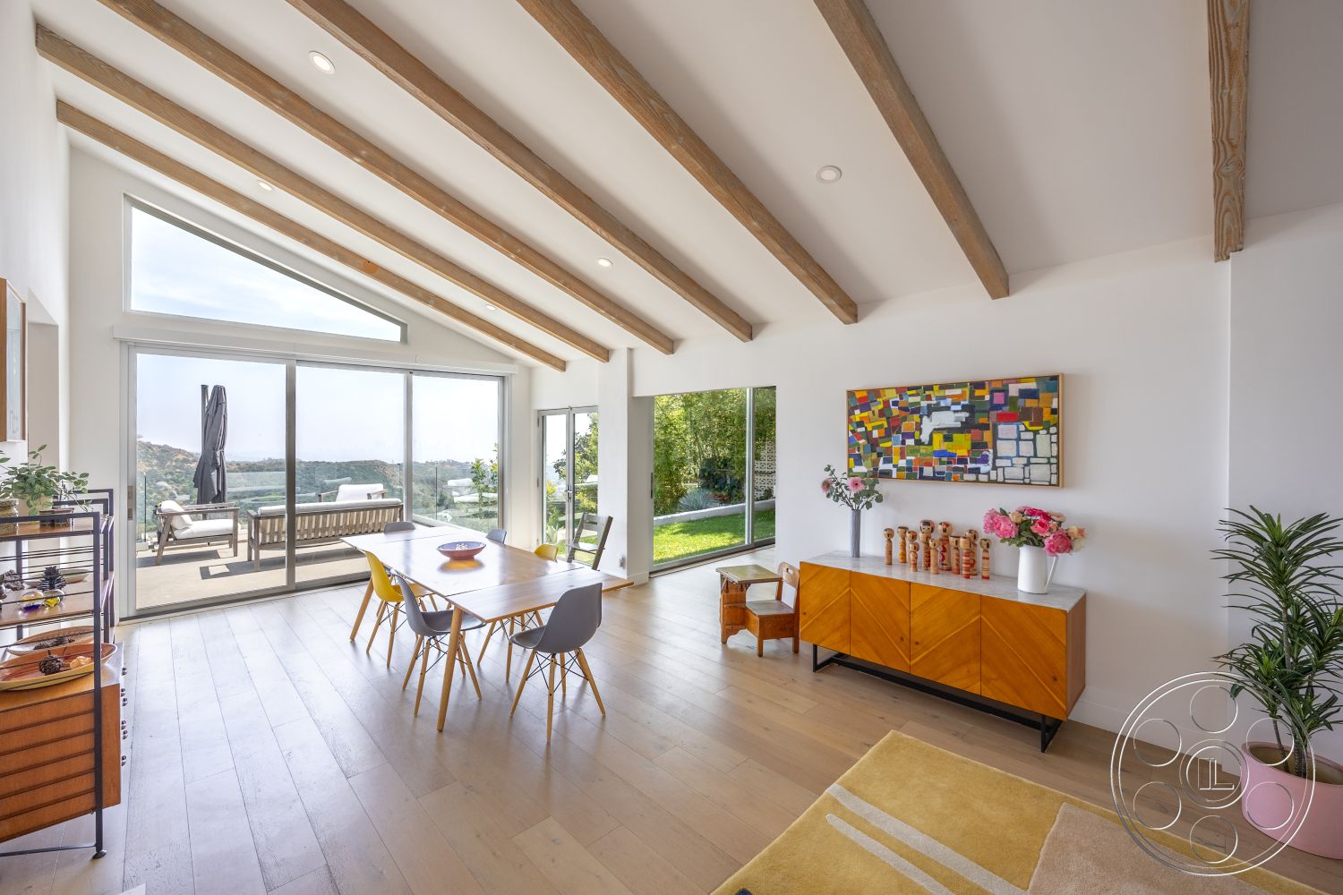 Retro 288 - light wood flooring, colorful wall art, sliding glass doors, minimalist furniture, floor-to-ceiling windows, open concept living space, lush greenery view, modern dining table, modern dining chairs, exposed wood ceiling beams, neutral painted walls, sunlit room, contemporary sideboard cabinet