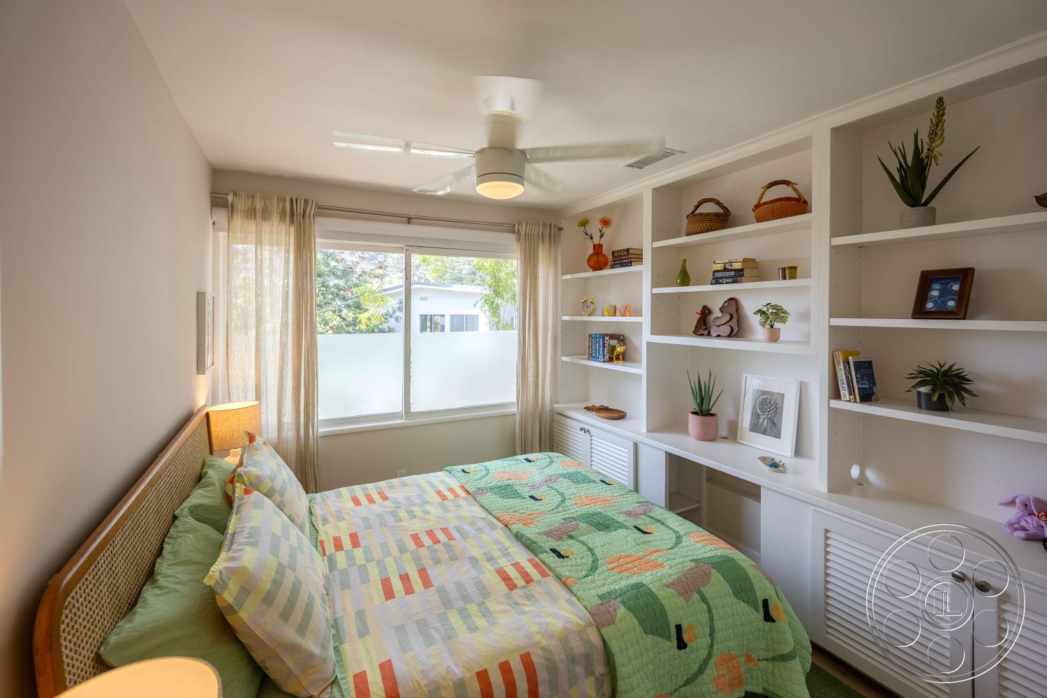 Retro 288 - neutral color palette, decorative plants, textured bedding, ceiling fan, woven baskets, glass window treatments, white painted walls, rectangular room layout, hardwood bed frame, soft lighting from bedside lamp, light wood built-in shelves, fresh floral decor