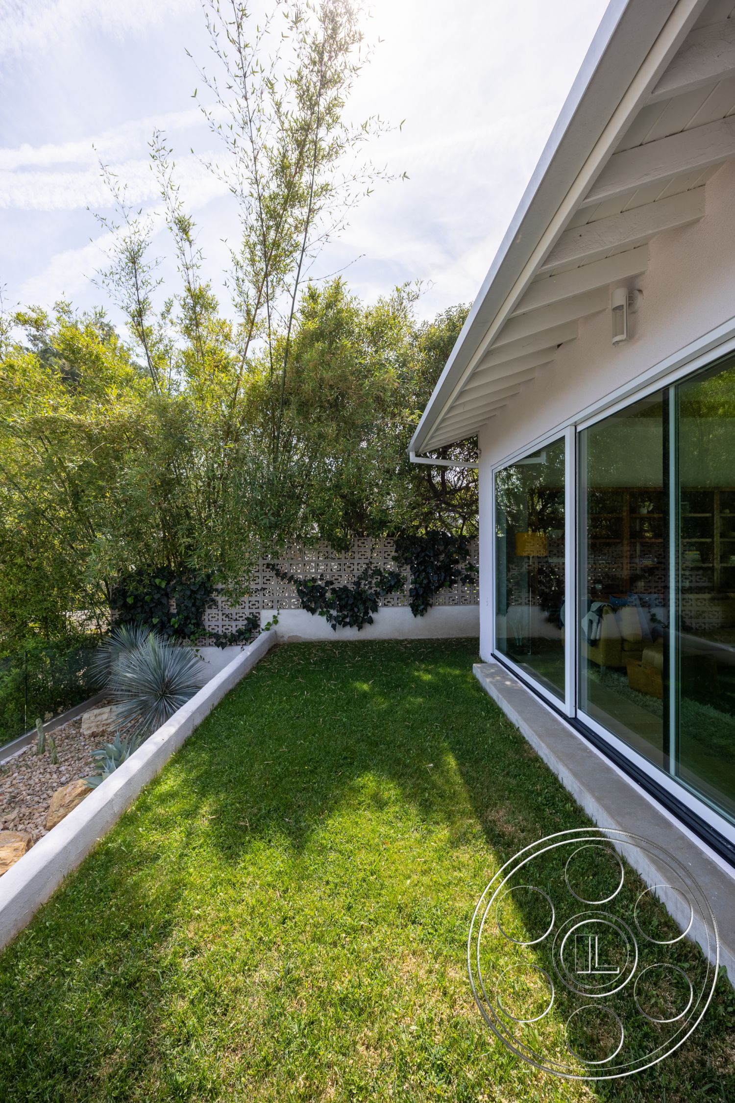 Retro 288 - exterior, landscaped garden, white stucco walls, flat roof, large glass windows, bamboo plants, lush green lawn, succulent landscaping, concrete foundation, decorative concrete block wall
