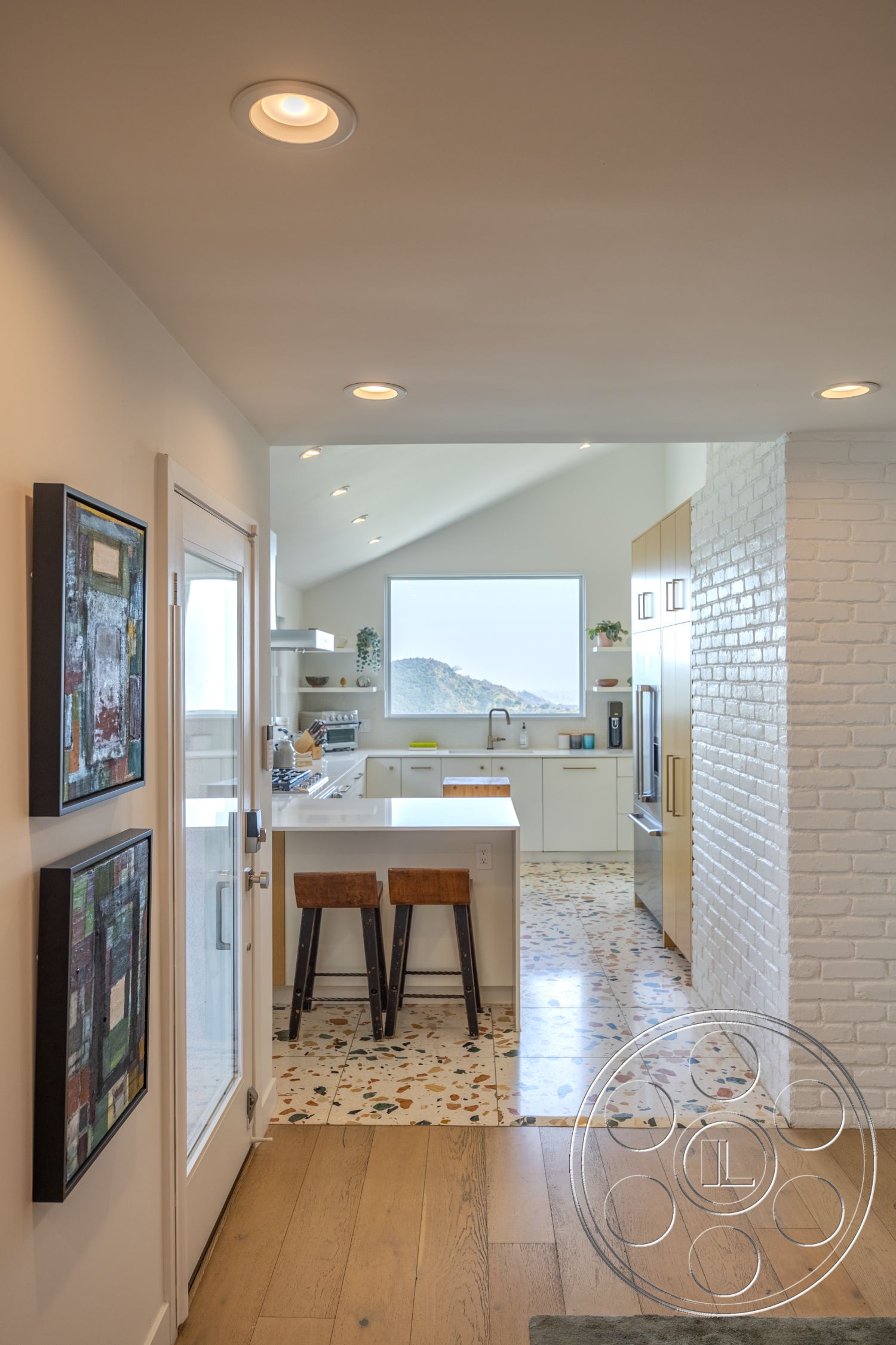 Retro 288 - exterior, contemporary design, stainless steel kitchen appliances, modern kitchen cabinetry, white painted walls, open floor plan kitchen, natural light flooding space, interior entryway, vaulted ceiling with recessed lighting, terrazzo kitchen flooring, light wood dining bar stools, exposed white brick wall, large window with mountain view