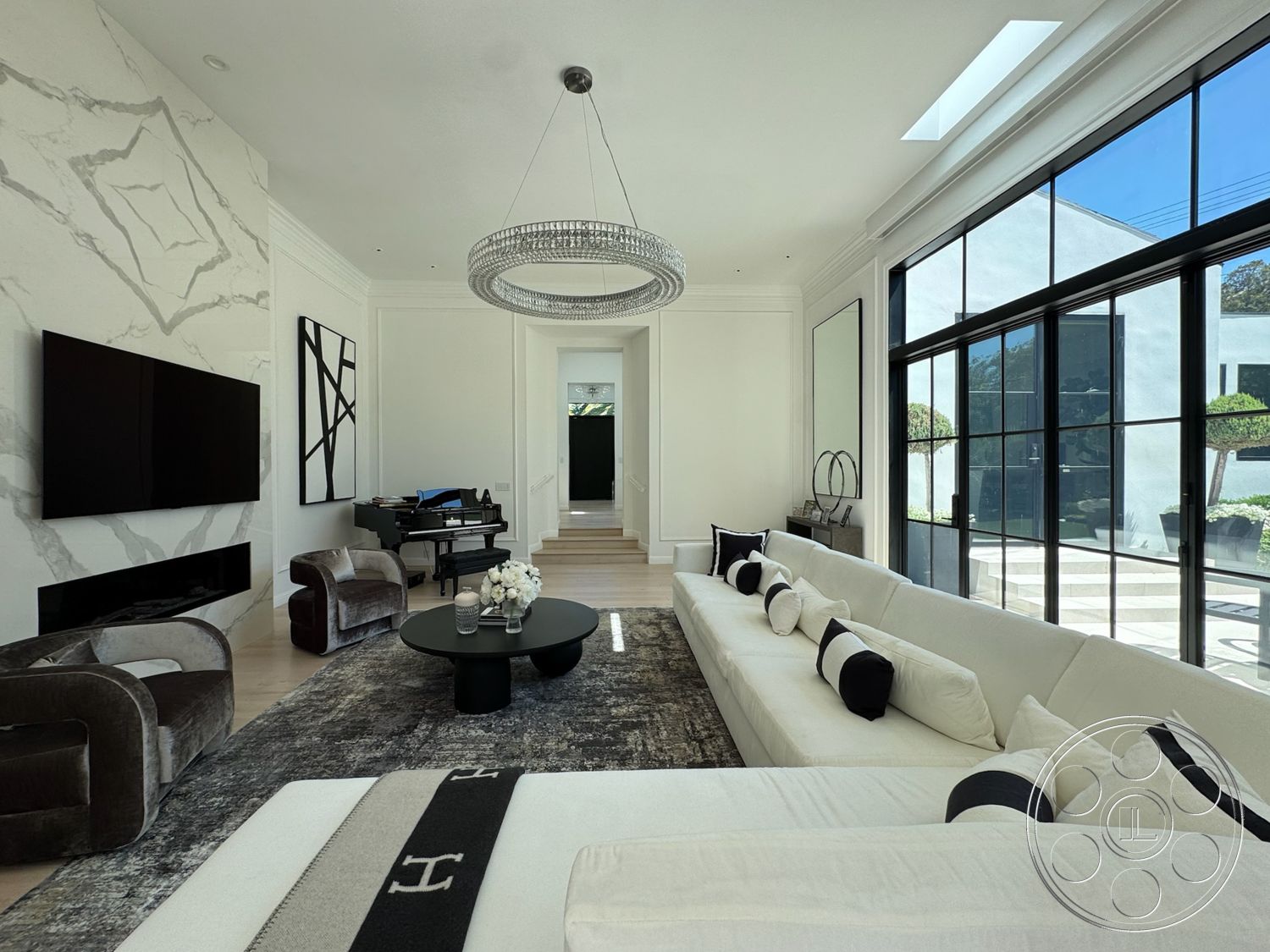 Modern 522 - minimalist decor, hardwood flooring, contemporary design, round coffee table, open floor plan, crystal chandelier, black leather sofa, marble accent wall, stylish armchairs, white painted walls, natural light abundance, piano in living room, glass panel windows, sleek black television, modern black fireplace, black and white accent pillows, smooth ceiling lines