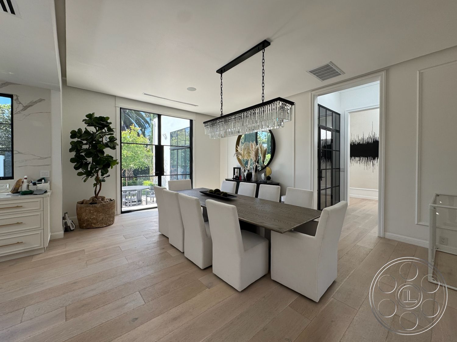 Modern 522 - textured wall art, upholstered dining chairs, rectangular dining table, black framed glass doors, white painted walls, hardwood dining room floors, round wall mirror, crystal pendant lighting, decorative plant in pot