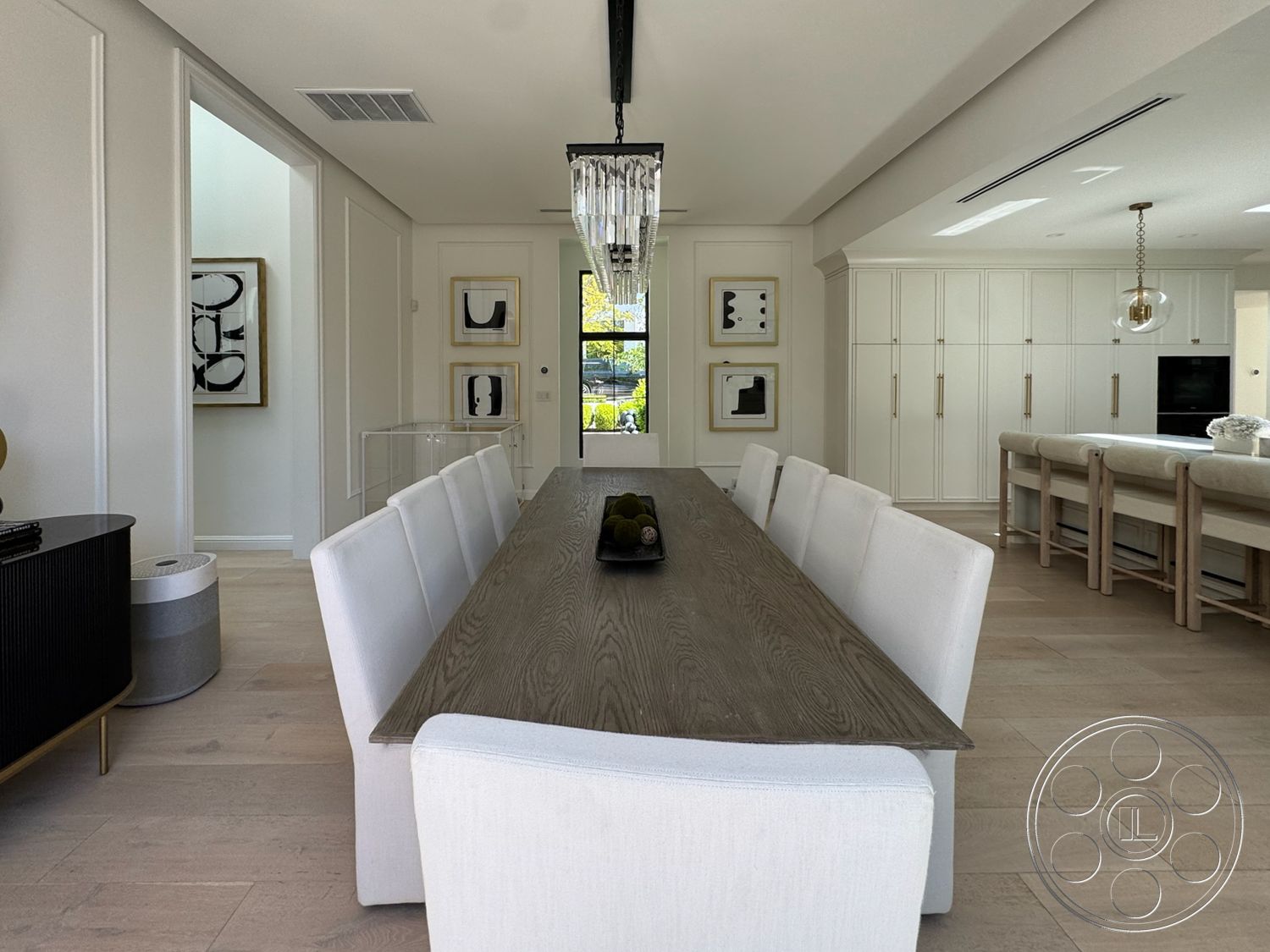 Modern 522 - floor-to-ceiling windows, open-concept layout, dark wood dining table, modern kitchen cabinetry, white painted walls, gold hardware details, framed abstract wall art, light hardwood dining room floors, upholstered white dining chairs, chandeliers with crystal accents, built-in pantry cabinets, cohesive neutral color palette