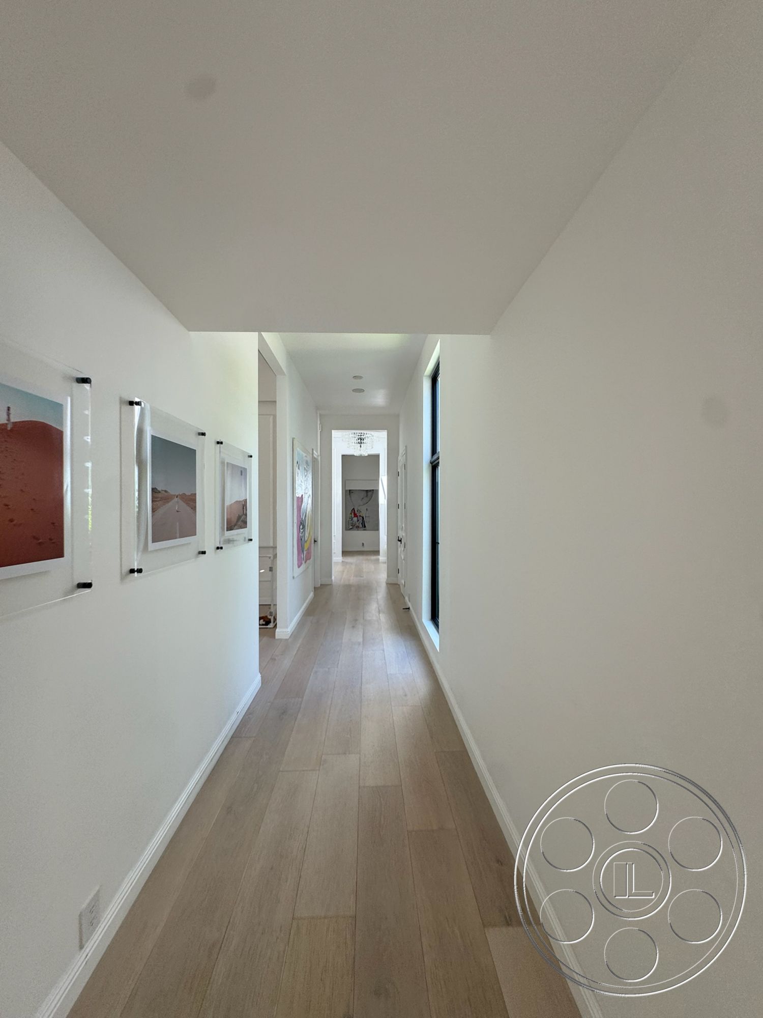 Modern 522 - natural light from windows, white painted walls, wooden hallway flooring, minimalist ceiling design, framed artwork on wall, linear corridor layout, doorway openings