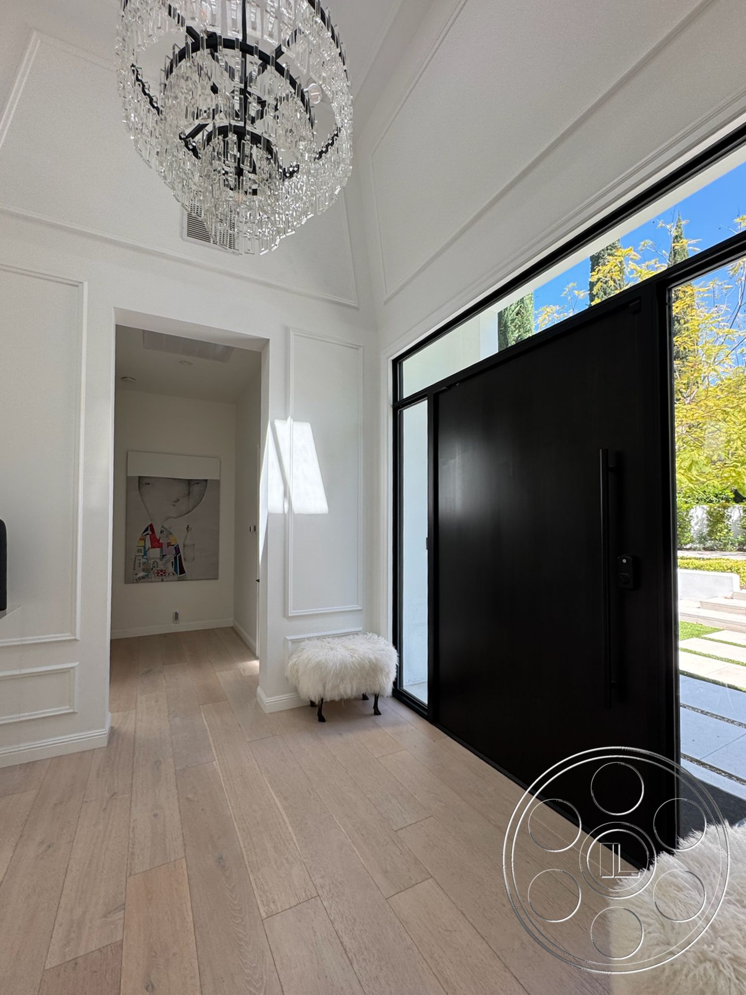 Modern 522 - minimalist aesthetic, artwork on wall, black front door, large floor-to-ceiling windows, exposed wood flooring, white painted walls, modern entryway design, chandelier lighting fixture