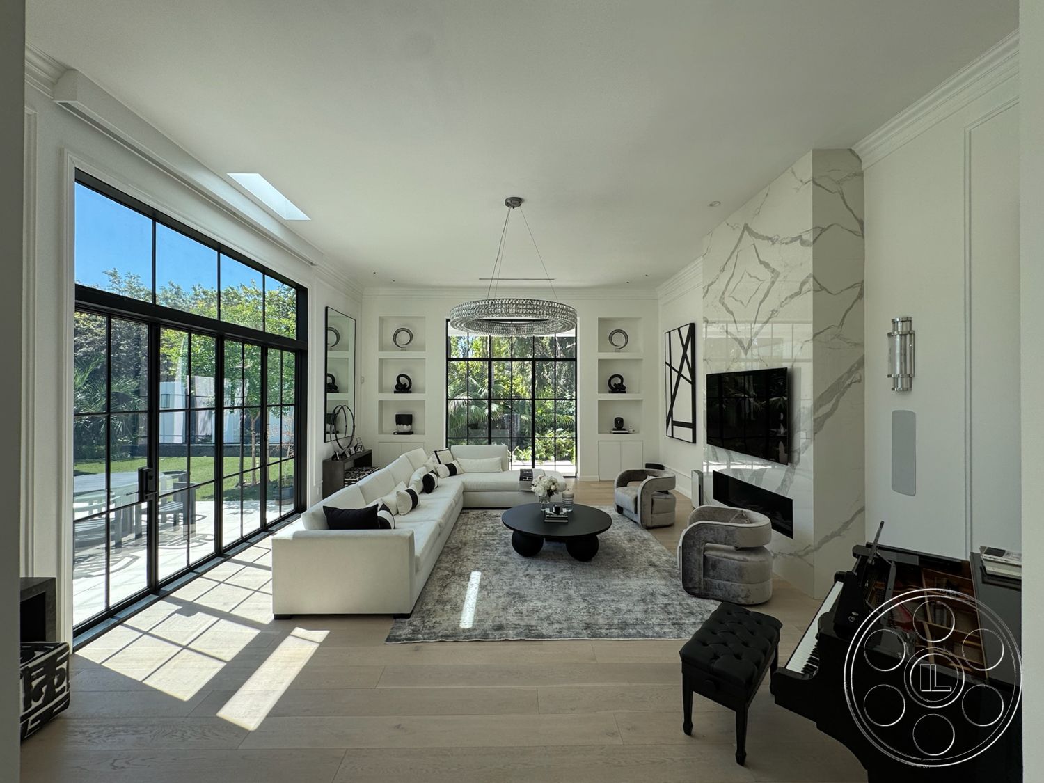 Modern 522 - high ceilings, white walls, neutral color palette, hardwood flooring, textured area rug, open floor plan, natural light from large windows, modern chandelier, marble feature wall, plush seating area, rectangular coffee table, stylish decor elements, gas fireplace, built-in shelving units, contemporary art accents, light wood trim, black windows with grid design, large glass doors to outdoor space