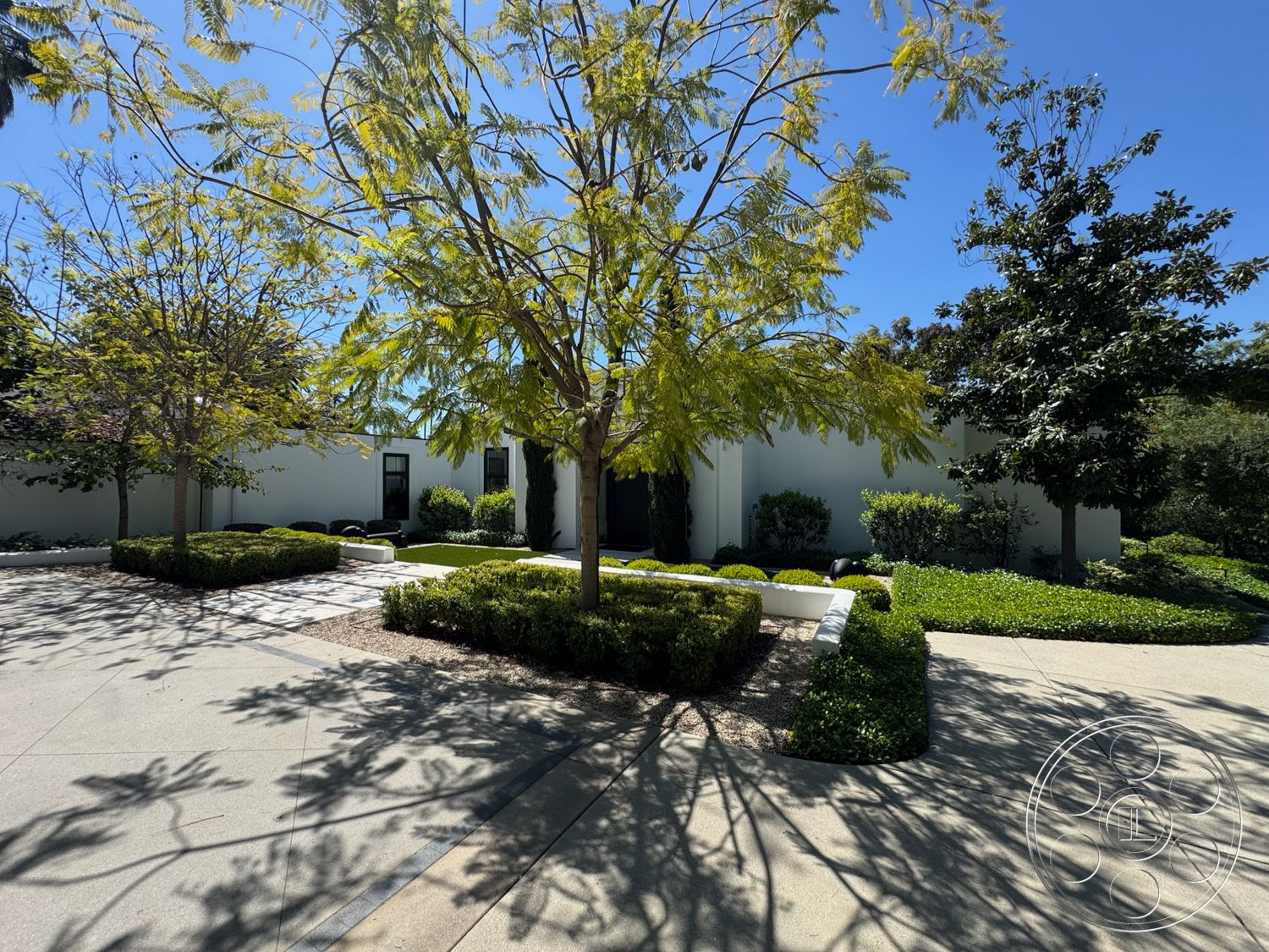 Modern 522 - exterior, white stucco walls, flat roof, concrete driveway, outdoor sitting area, tree canopies, landscaped garden beds, modern minimalist architecture, hedge greenery landscaping, paved decorative stone pathway