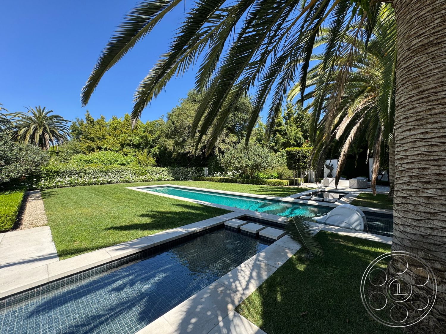 Modern 522 - exterior, lush green lawn, clear blue sky, tropical palm trees, rectangular pool, landscaped garden area, stone patio flooring, concrete pool border, minimalist outdoor furniture, hardscaped walkway, modern outdoor aesthetic, tile pool decking, surrounding lush shrubs