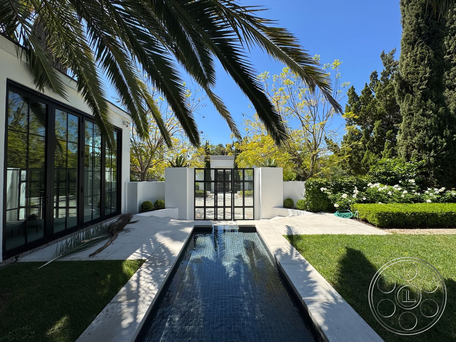 Modern 522 - exterior, white stucco walls, glass sliding doors, stone pathway, lawn area, tall palm trees, manicured hedges, landscaped garden area, concrete patio flooring, rectangular water feature, framed black metal windows