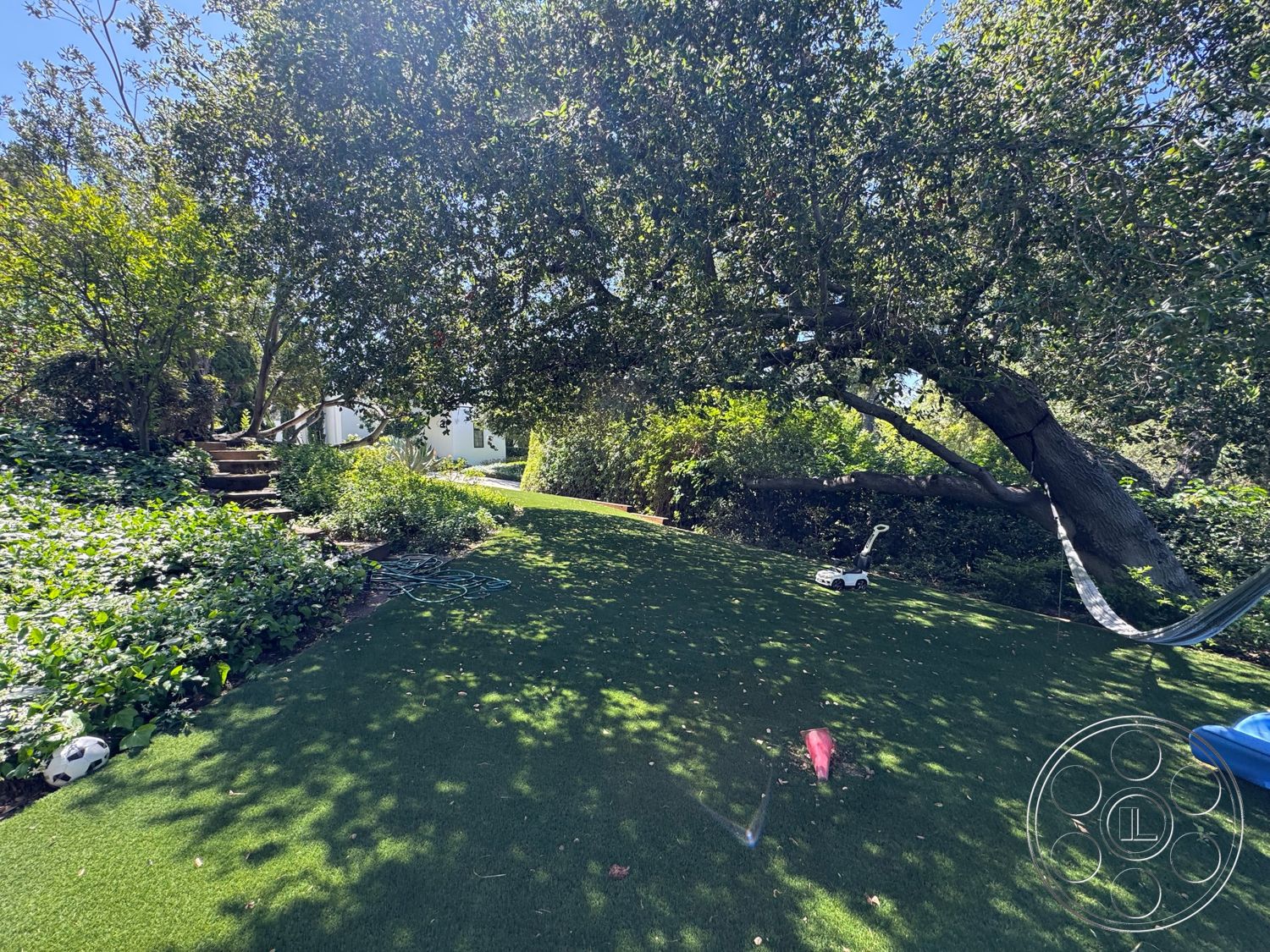 Modern 522 - exterior, landscaped garden, lush greenery, mature trees, flowering shrubs, suburban backyard, natural stone steps, open yard space, synthetic grass lawn, hammock hanging between trees