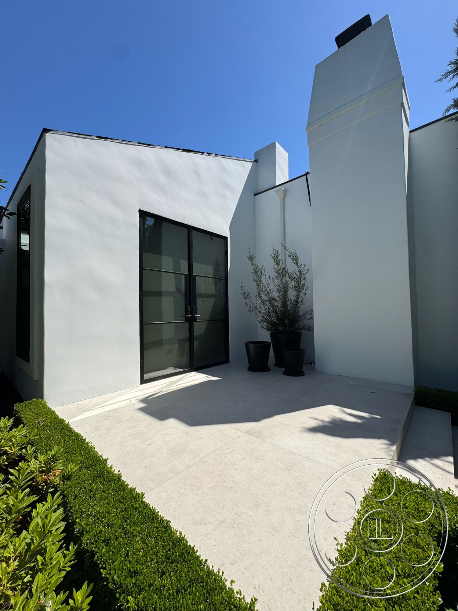 Modern 522 - exterior, white stucco walls, modern architectural style, glass entry door, black planter pots, sliding glass windows, flat roof design, landscaped garden beds, concrete patio floor, angular building shape