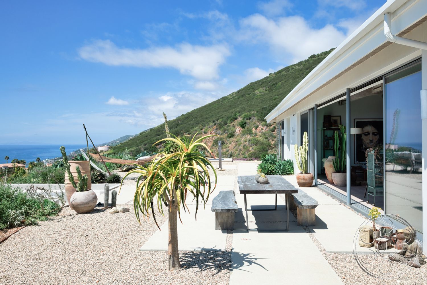 Modern 523 - exterior, lush greenery, glass sliding doors, wooden planter boxes, ocean view, hillside location, stone planters, concrete patio flooring, gravel garden path, modern home architecture, desert landscaping with cacti, slate outdoor dining table, terraced yard