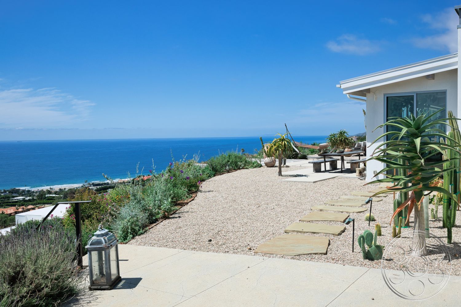 Modern 523 - exterior, green plants, modern architectural style, gravel landscaping, ocean view, potted succulents, flagstone pathway, concrete patio floor, wooden outdoor dining table