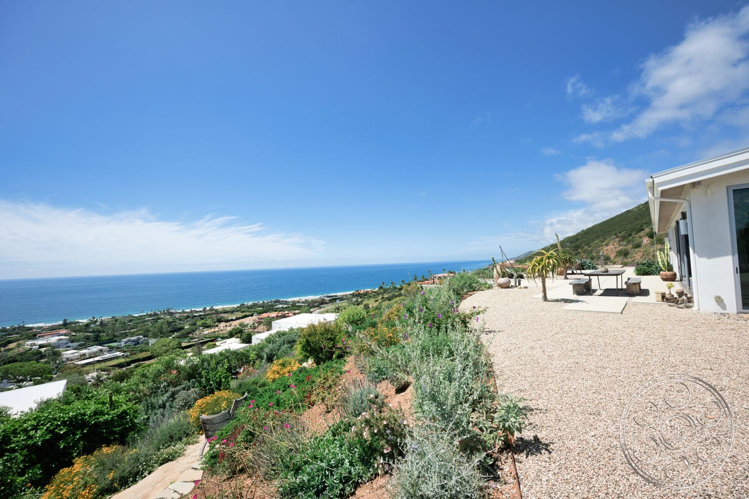 Modern 523 - exterior, mountain backdrop, landscaped garden area, gravel patio flooring, modern home architecture, low-maintenance shrubs, oceanview setting, concrete table surface, sun-soaked terrace, sweeping coastal view