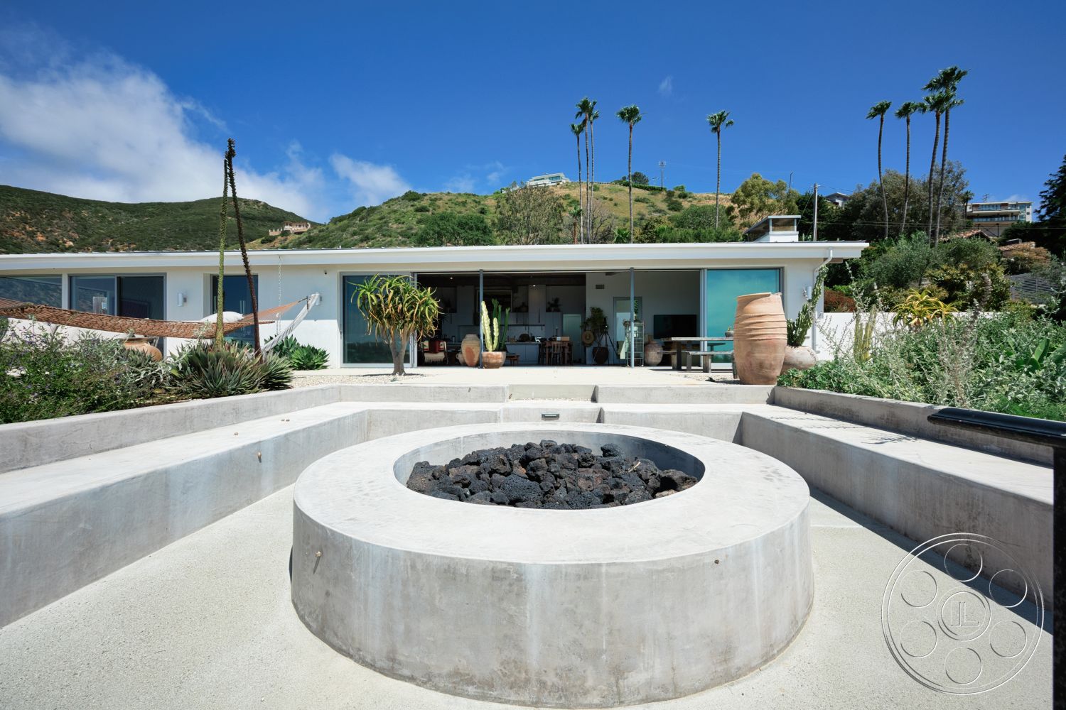 Modern 523 - exterior, landscaped garden, smooth concrete surface, floor-to-ceiling windows, single-story home, outdoor lounge area, modern architectural style, arched doorway, concrete seating area, concrete fire pit, desert plant landscaping, sandstone patio flooring, highland view setting