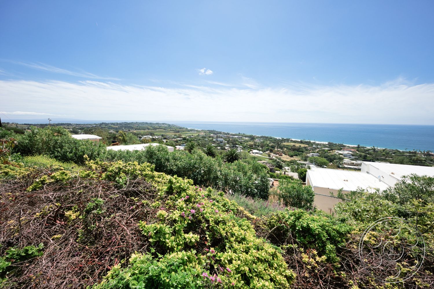 Modern 523 - exterior, lush greenery, flowering shrubs, ocean view, blue sky, hilly landscape, tropical vegetation, residential rooftops, distant coastline