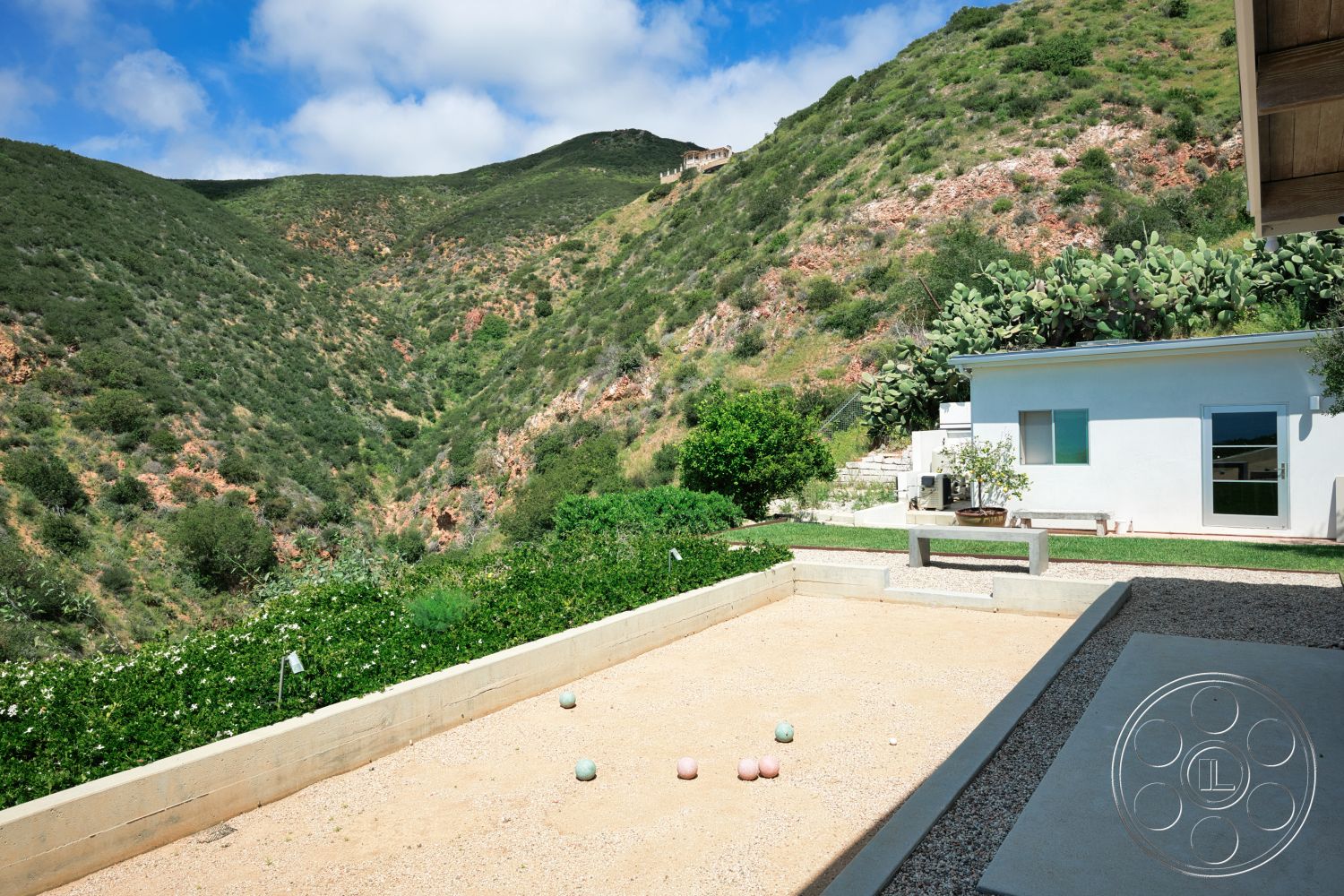 Modern 523 - exterior, large glass windows, surrounding hillside, gravel landscaping, flat roof design, mountain view setting, integrated outdoor seating area, native plant landscaping, minimalist home design, concrete bocce ball court, modern white home