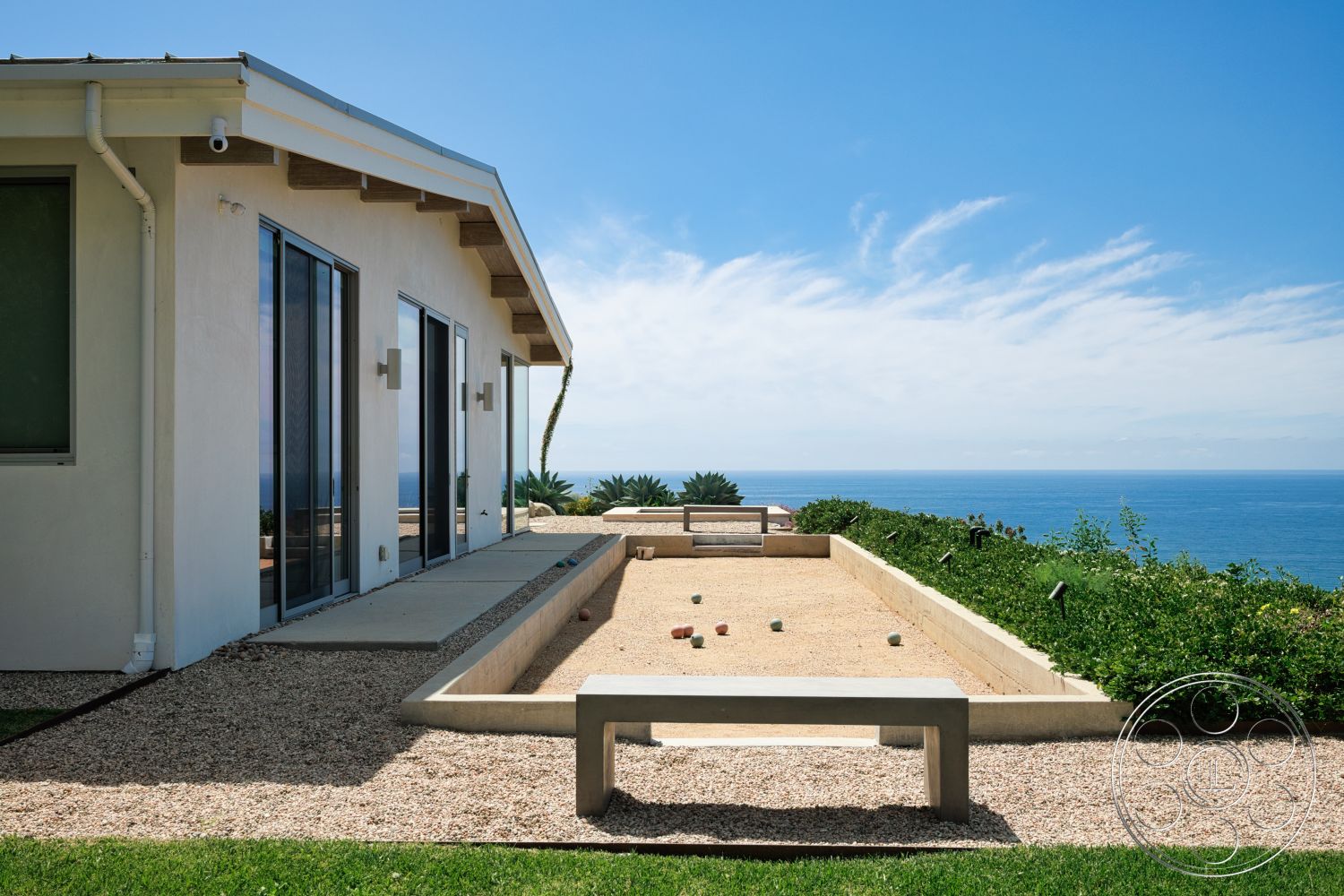 Modern 523 - exterior, landscaped garden, glass sliding doors, modern architectural style, gravel landscaping, ocean view, wood beam roof overhang, concrete patio floor, stucco house walls, outdoor bocce court