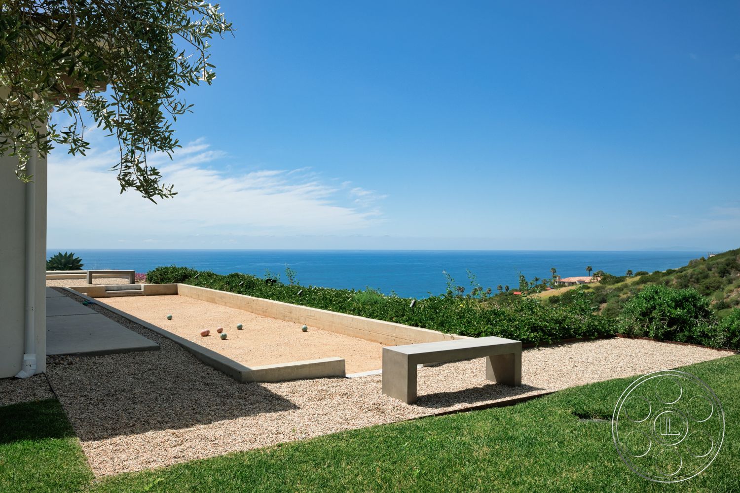 Modern 523 - exterior, minimalist design, lush landscaping, ocean view, hillside location, sunny outdoor setting, concrete bench, gravel patio flooring, green grass area, concrete bocce ball court