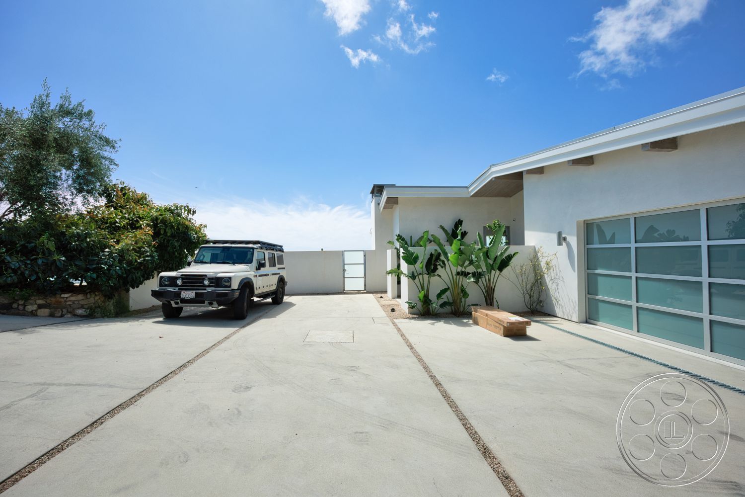 Modern 523 - exterior, modern architecture, stone accent wall, concrete driveway, minimalistic design elements, flat roof design, landscaped garden with tropical plants, floor-to-ceiling glass garage door, horizontal wood slats on eaves, gated entry wall