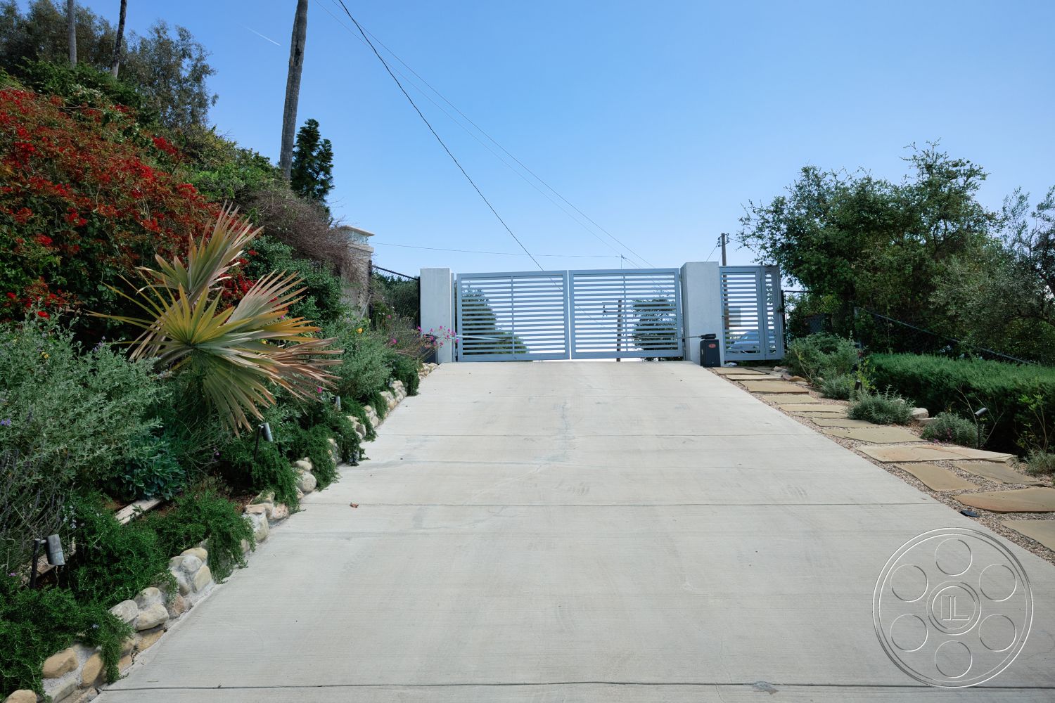 Modern 523 - exterior, landscaped garden, metal gate, concrete driveway, sloped driveway, succulent plants, residential setting, urban hillside location, stone border landscaping, decorative shrubbery, horizontal slatted gate design