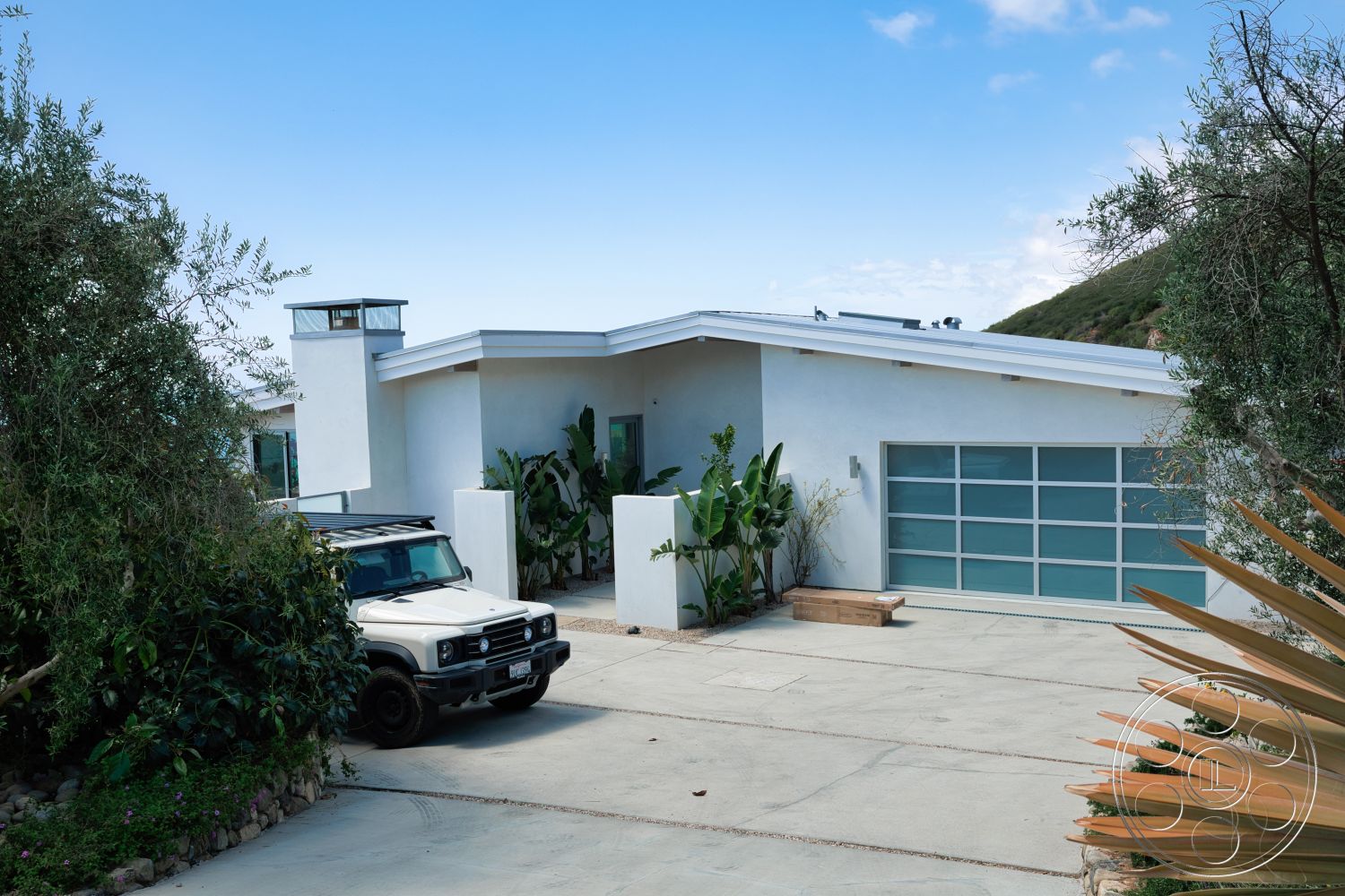 Modern 523 - exterior, geometric shapes, modern architectural style, concrete driveway, stucco walls, large glass garage door, flat roof design, natural stone border, landscaped garden with tropical plants, minimalistic façade