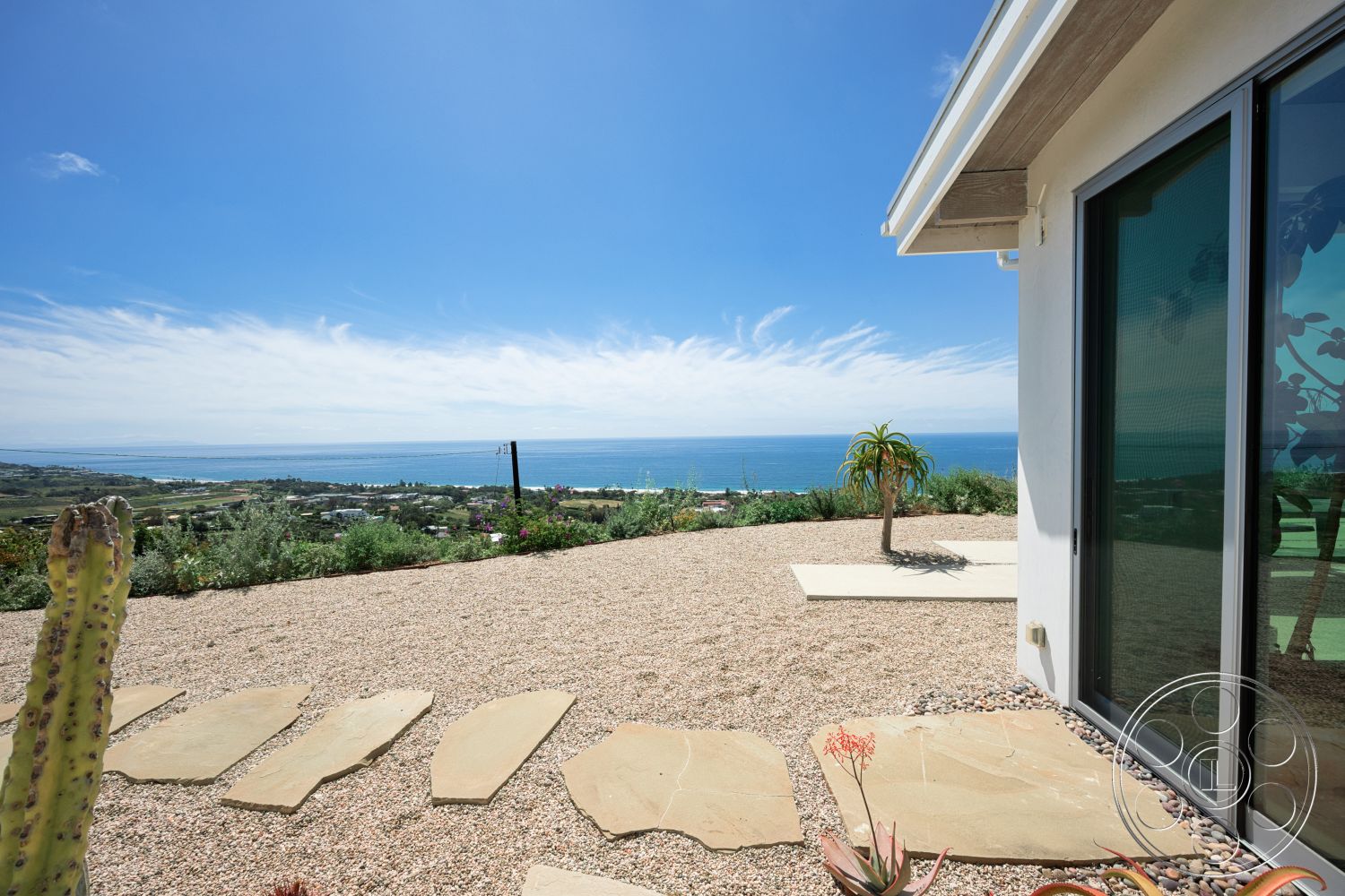 Modern 523 - exterior, large glass windows, tropical plants, low-maintenance garden, gravel landscaping, ocean view, desert setting, flat roof design, modern home architecture, sunny outdoor environment, stucco wall finishes, stone pathway stepping stones
